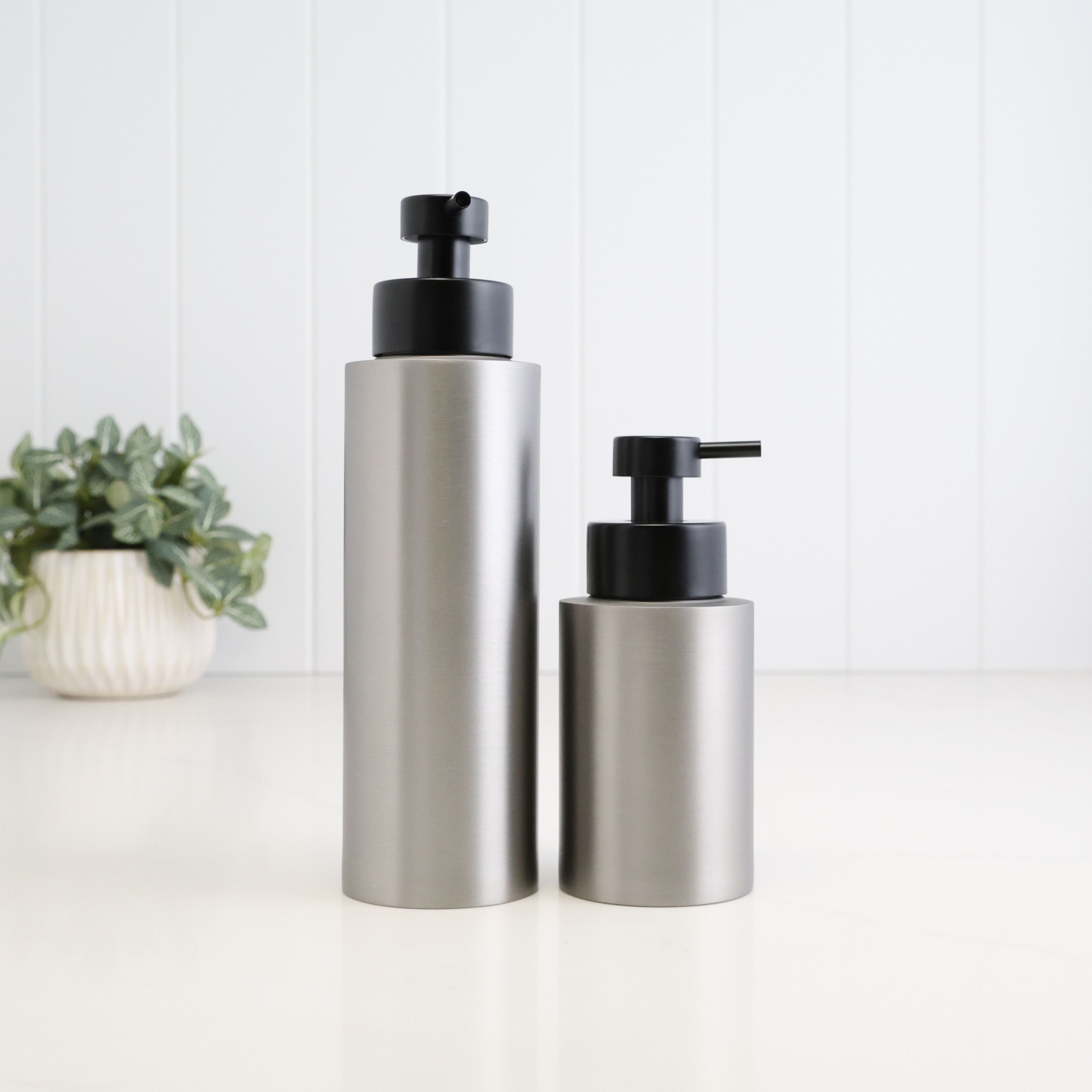 250ml and 500ml brushed 304 stainless steel refillable soap dispensers shown together for size comparison, both featuring a modern cylindrical design and satin black liquid pumps for bathroom, kitchen or shower use.