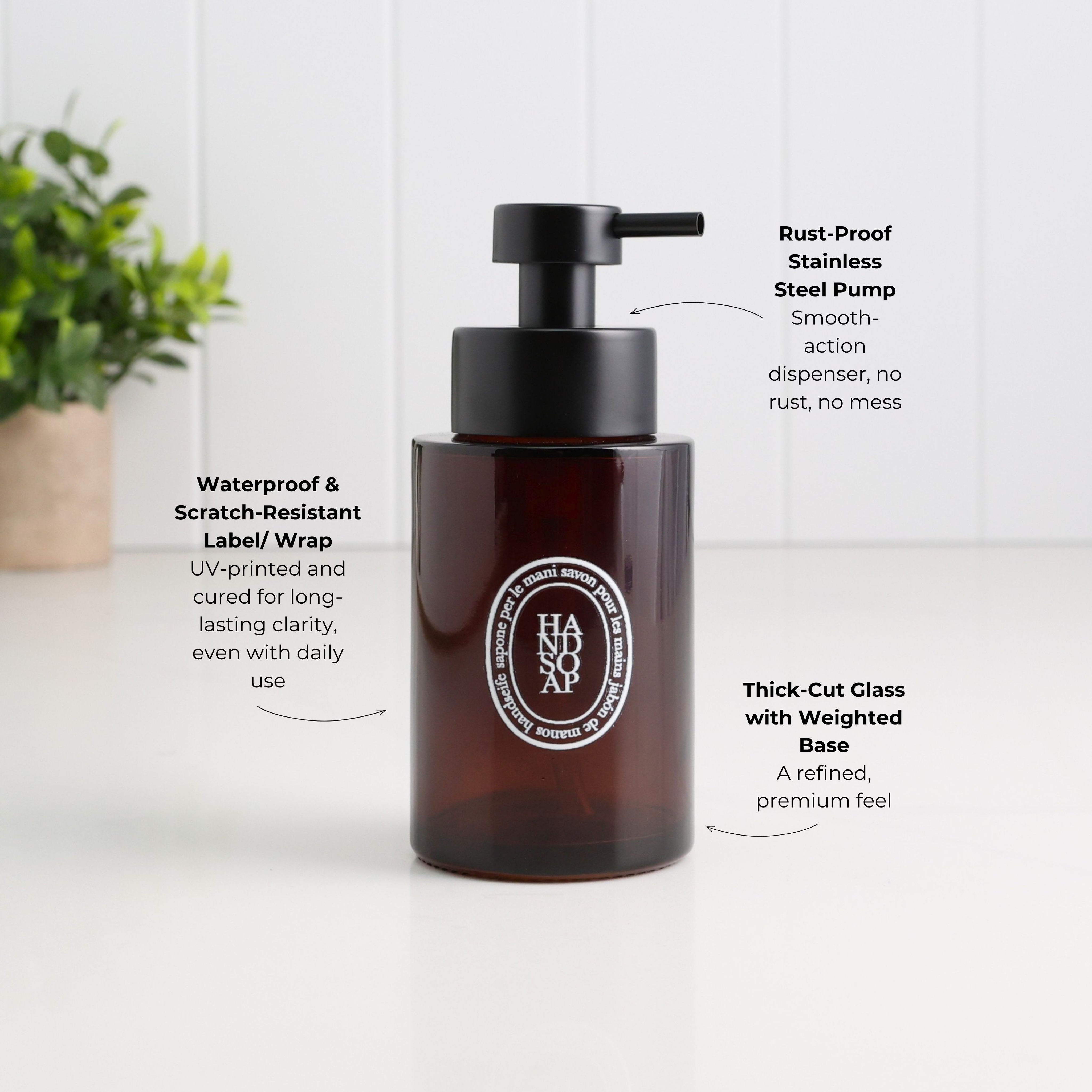 250ml amber glass refillable hand soap dispenser with white oval label and satin black stainless steel liquid pump, highlighting its thick-cut weighted glass base and waterproof, scratch-resistant UV-printed label.