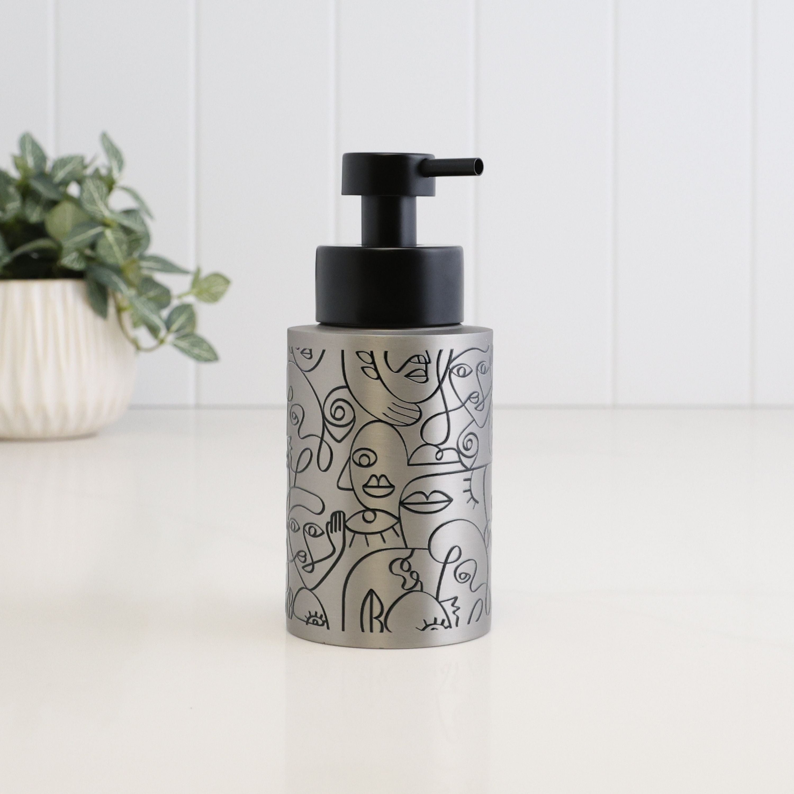 250ml brushed 304 stainless steel soap dispenser with black abstract face line art and satin black liquid pump, designed as a refillable dispenser for bathroom, kitchen or cloakroom use.