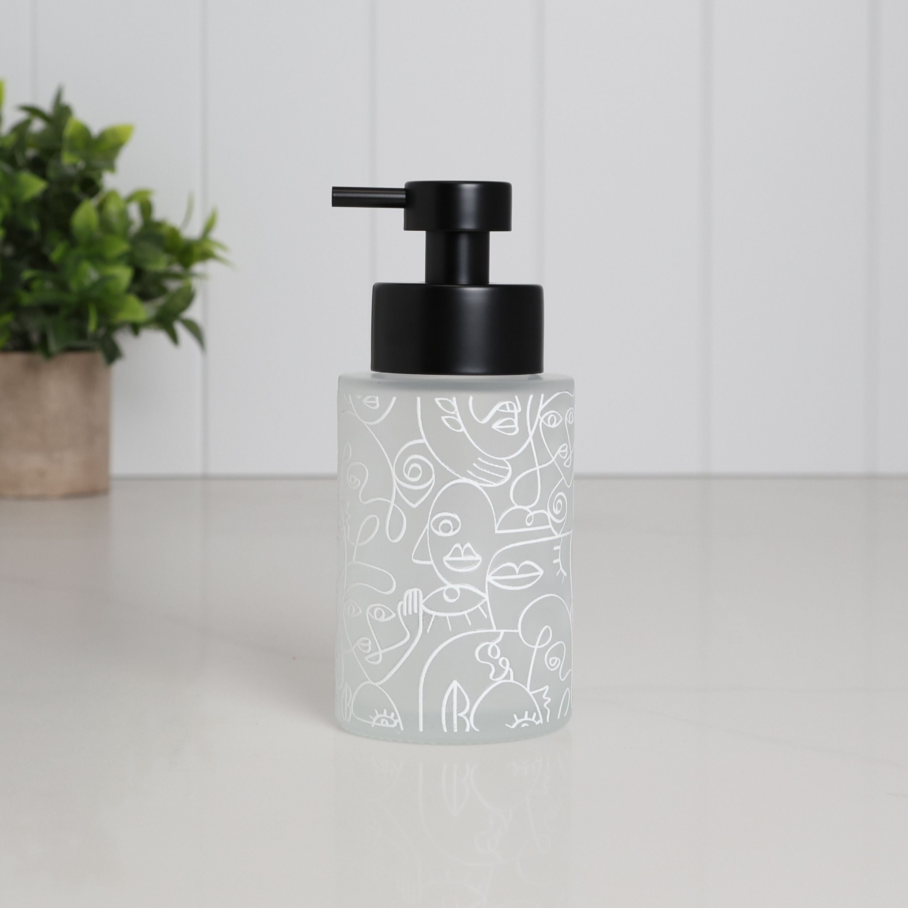 Frosted glass soap dispenser with abstract face line art wrap, 250ml bathroom pump bottle with matte black stainless steel top, modern refillable hand wash container for minimalist sink decor, reusable lotion dispenser with artistic pattern, eco friendly bathroom accessory on clean white countertop