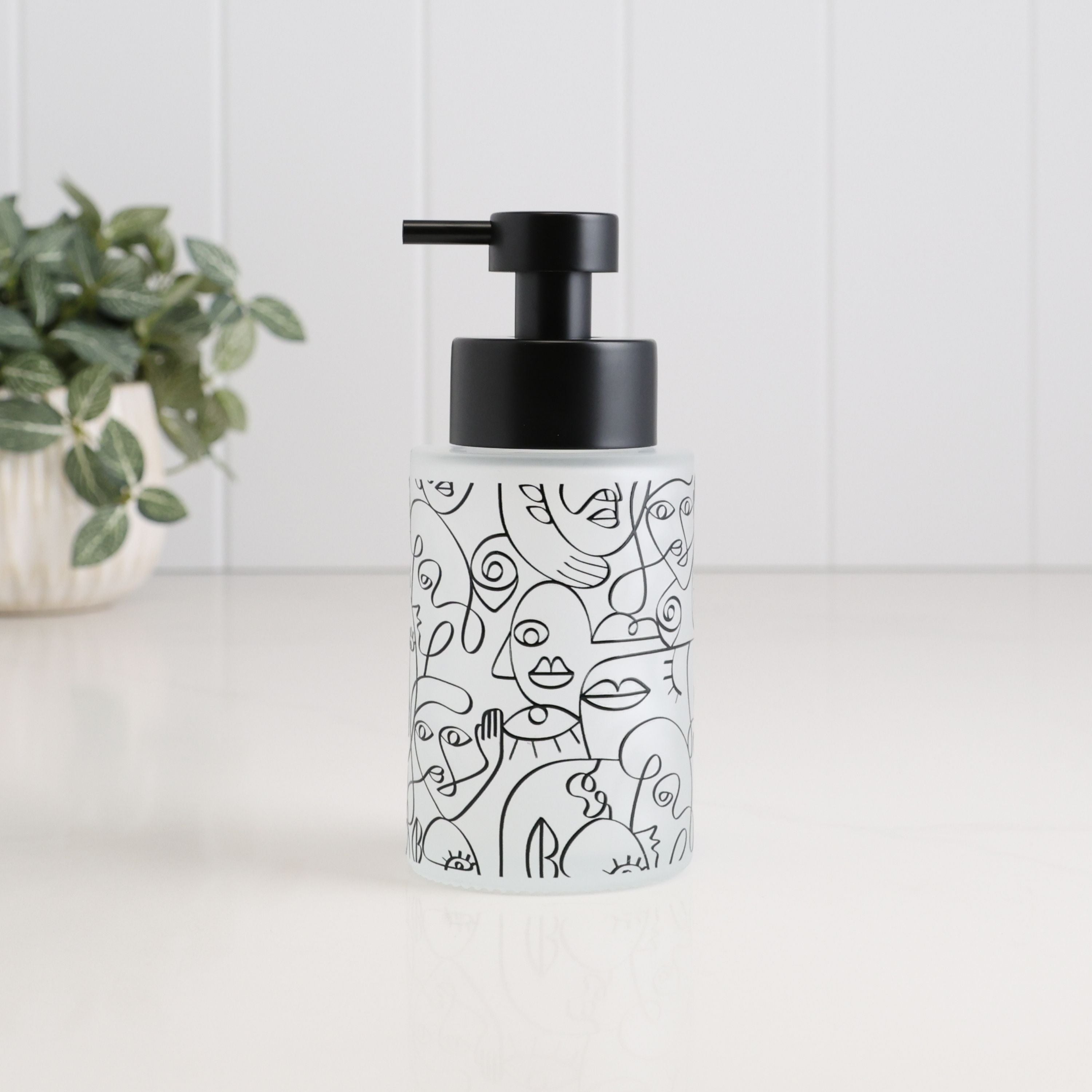250ml frosted glass soap dispenser with black abstract face line art and satin black pump, a compact refillable hand soap or lotion bottle for bathroom sinks, ensuites and cloakrooms.
