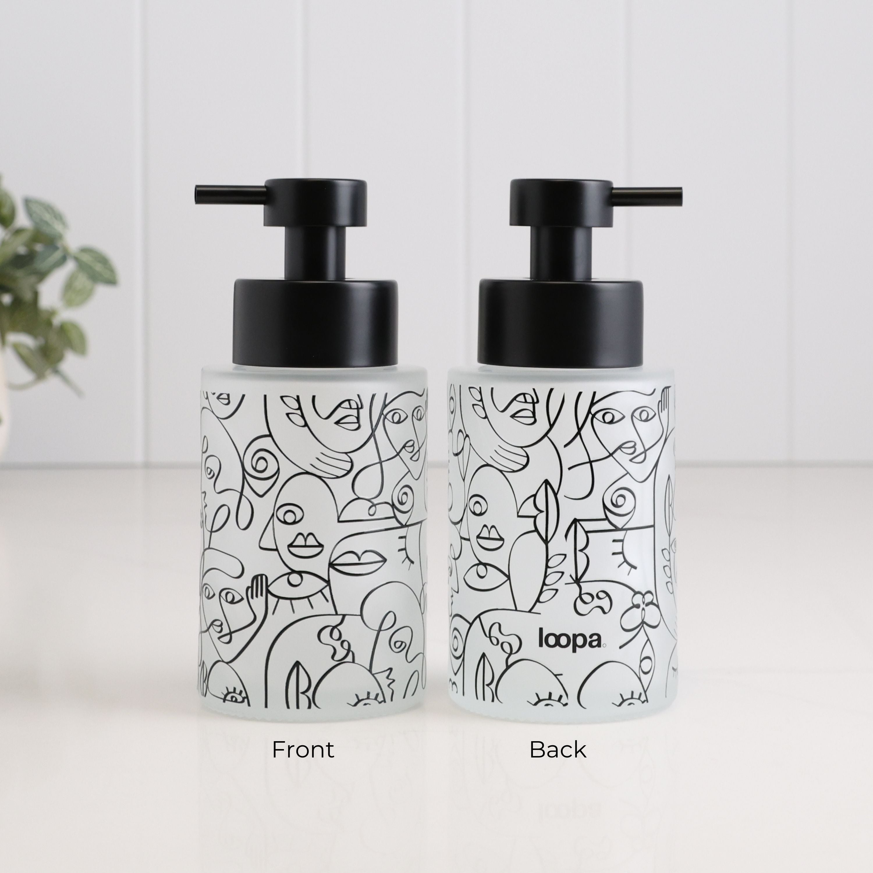 Front and back views of a 250ml frosted glass soap dispenser with black abstract face line art, satin black pump and Loopa branding, designed as a refillable hand soap or lotion dispenser for modern bathrooms and kitchens.