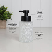 Frosted glass soap dispenser with abstract face illustration wrap, refillable 250ml bathroom bottle featuring black stainless steel pump, waterproof scratch resistant UV printed design for long lasting clarity, thick weighted glass base for stability, modern reusable hand wash or lotion dispenser for minimalist sink styling