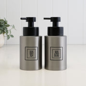 Matching 250ml brushed 304 stainless steel hand soap and hand lotion dispensers with black square labels and satin black pumps, styled as a refillable bathroom or kitchen sink set.