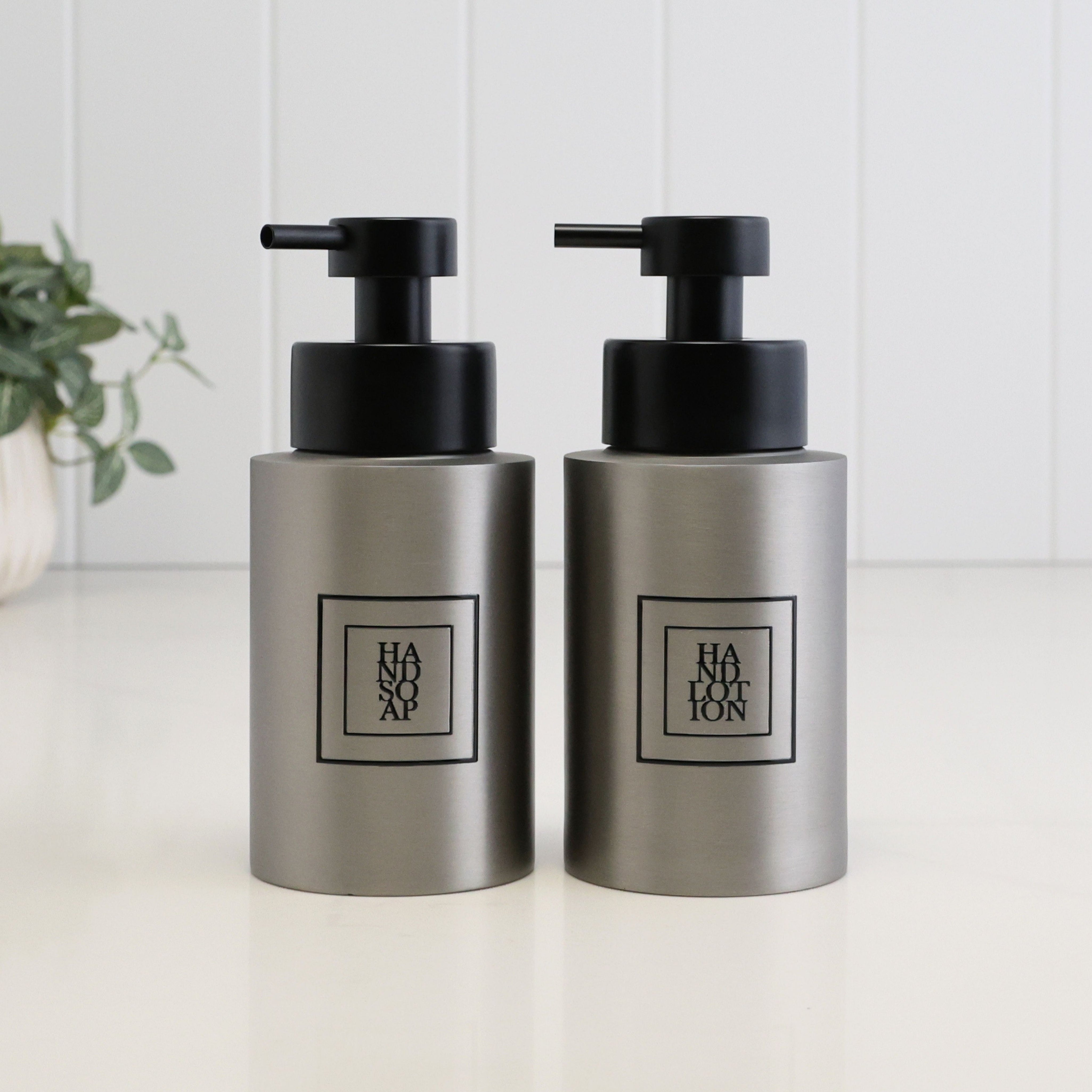 Matching 250ml brushed 304 stainless steel hand soap and hand lotion dispensers with black square labels and satin black pumps, styled as a refillable bathroom or kitchen sink set.