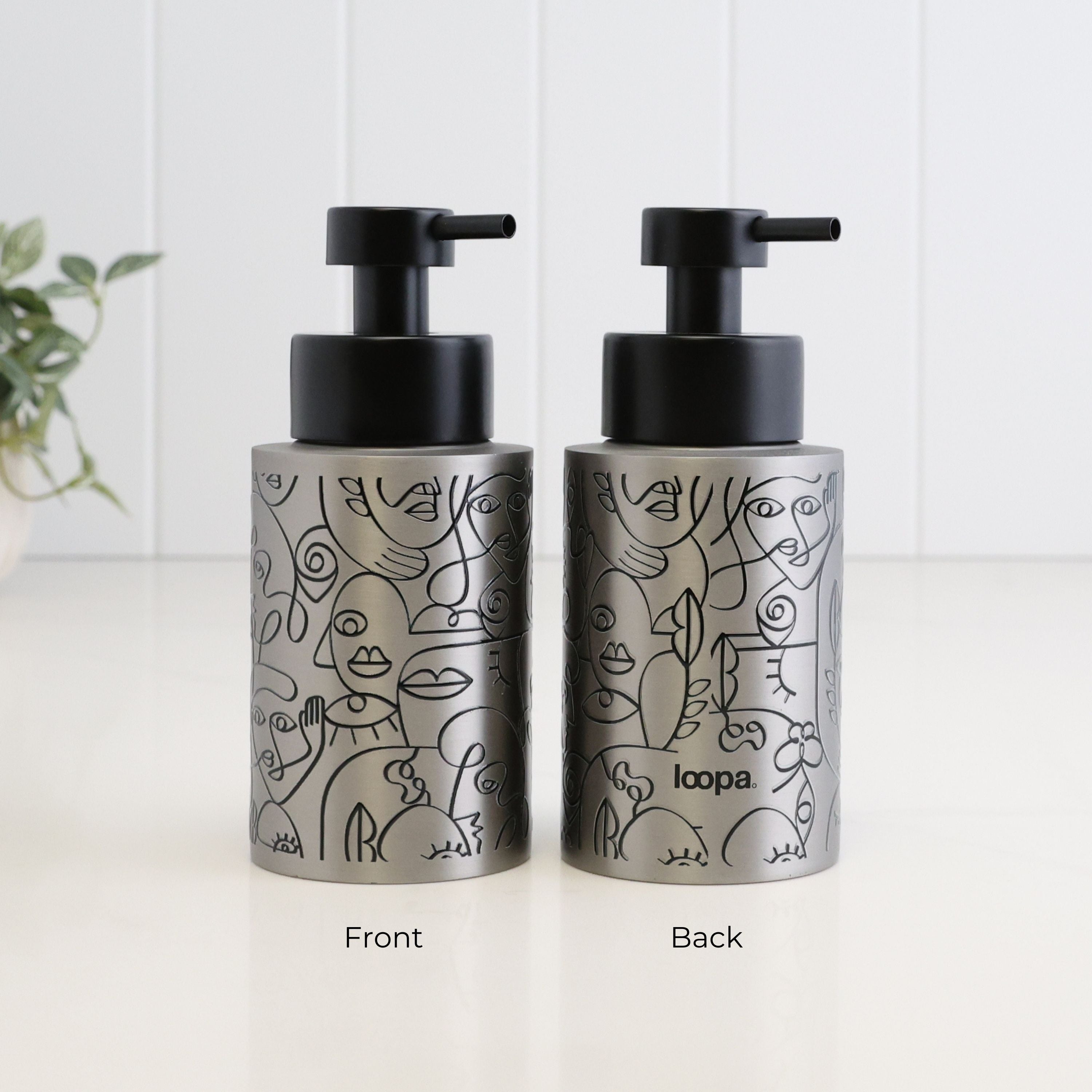 Front and back view of a 250ml brushed 304 stainless steel soap dispenser with black abstract face line art, satin black liquid pump and subtle Loopa branding on the reverse.