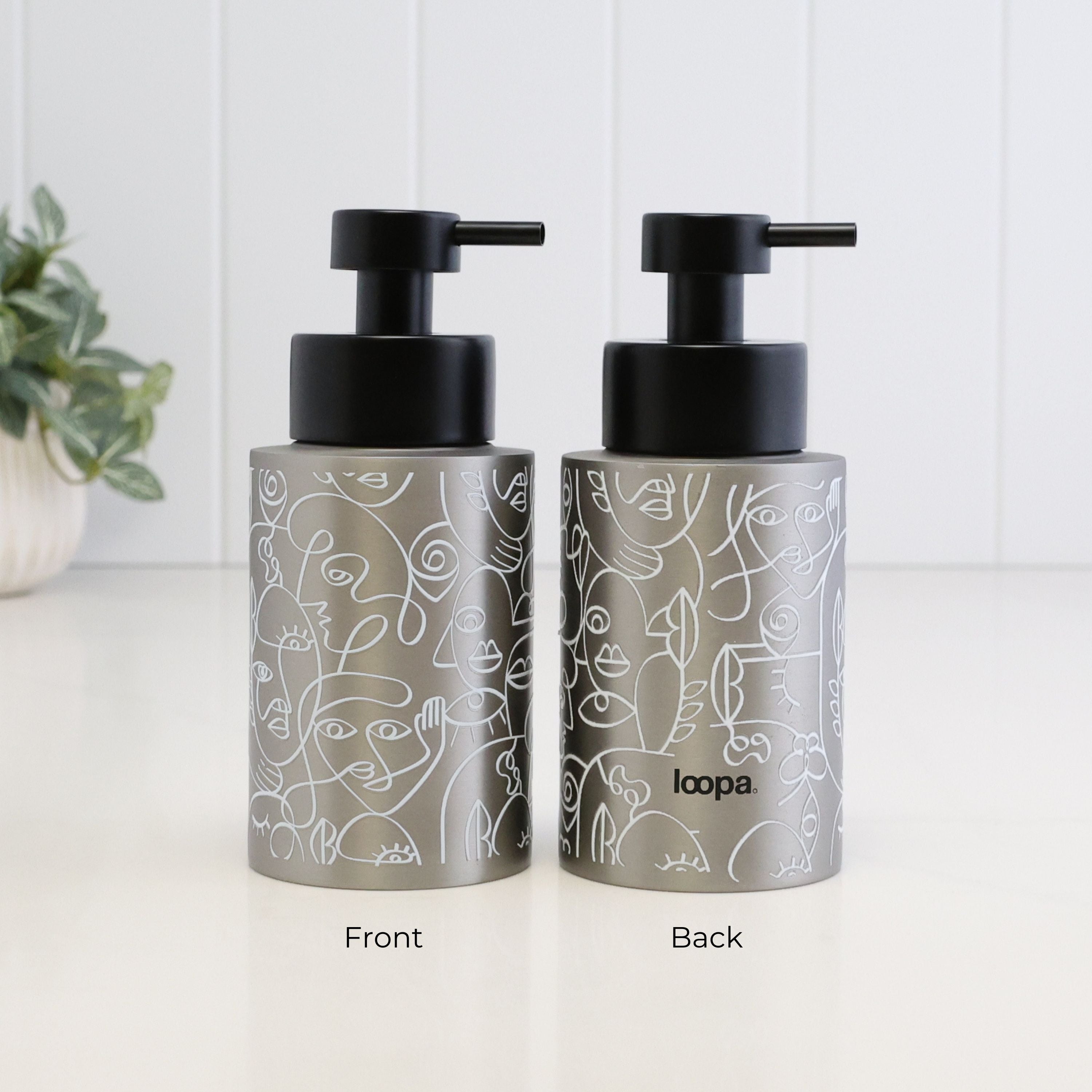 Front and back view of a 250ml brushed 304 stainless steel soap dispenser with white abstract line art, satin black liquid pump and Loopa branding, showing the decorative wrap around the refillable bottle.