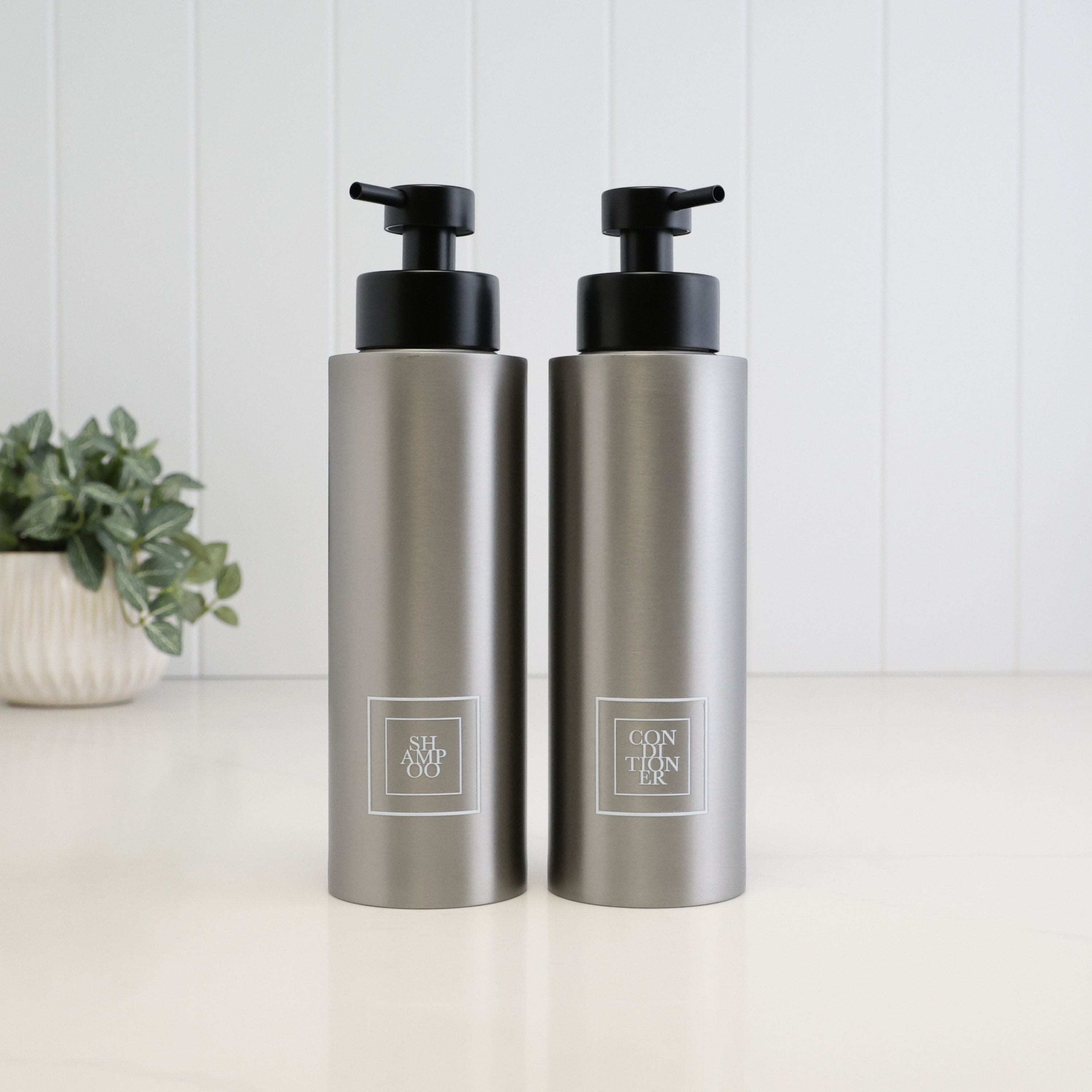 Pair of 500ml brushed 304 stainless steel shower dispensers with white square Shampoo and Conditioner labels, finished with satin black liquid pumps for a coordinated bathroom set.