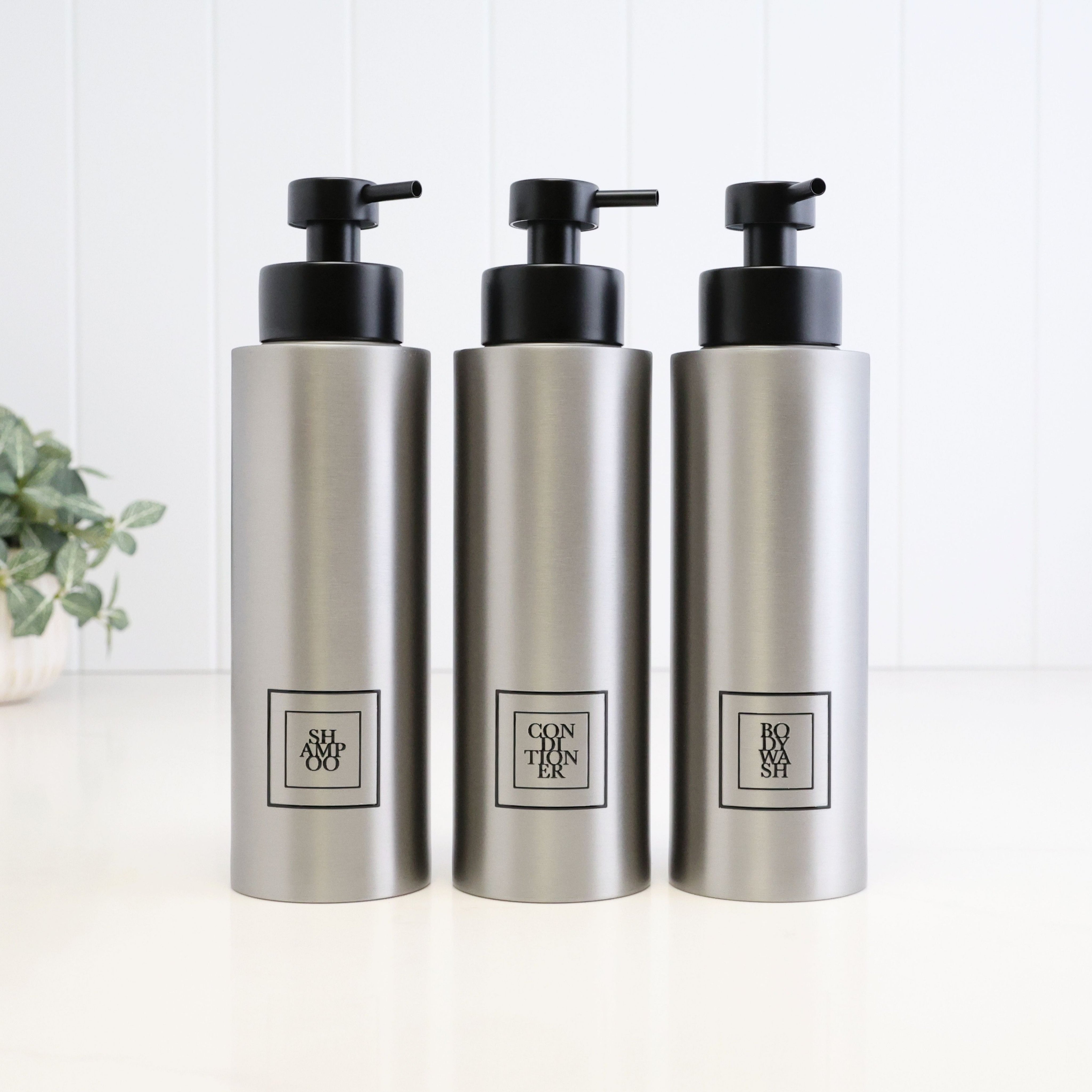 Set of three 500ml brushed 304 stainless steel dispensers for shampoo, conditioner and body wash, with black square labels and satin black liquid pumps for a coordinated shower or bathroom.