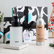 Two bottles of Loopa products with a decorative box and Christmas decorations in the background.
