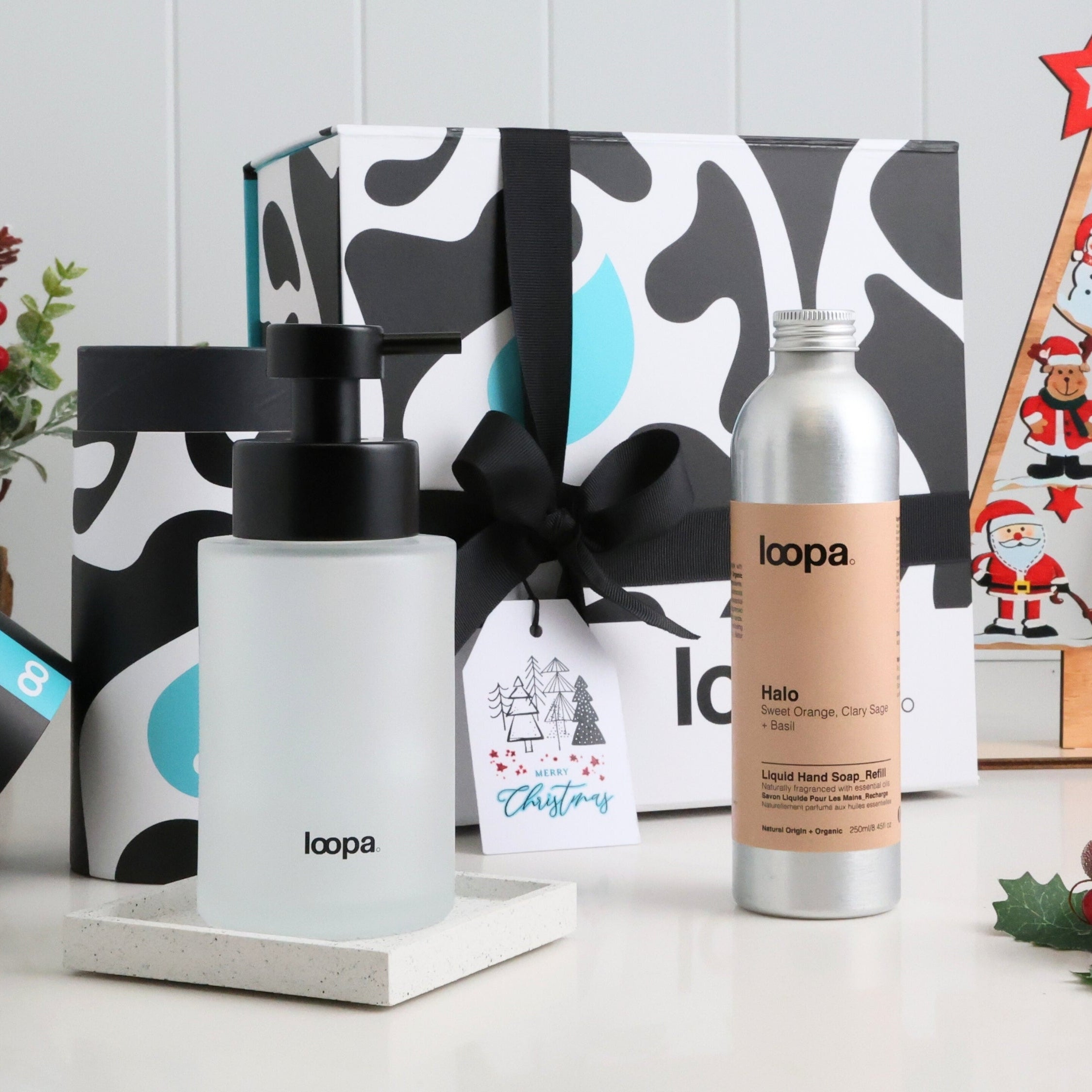 Two bottles of Loopa products with a decorative box and Christmas decorations in the background.