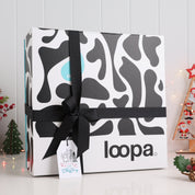 Premium Loopa Christmas gift box wrapped with black ribbon and festive tag, displayed among holiday décor. Elegant eco-friendly packaging perfect for luxury Christmas presents, seasonal home gifts and winter celebrations.