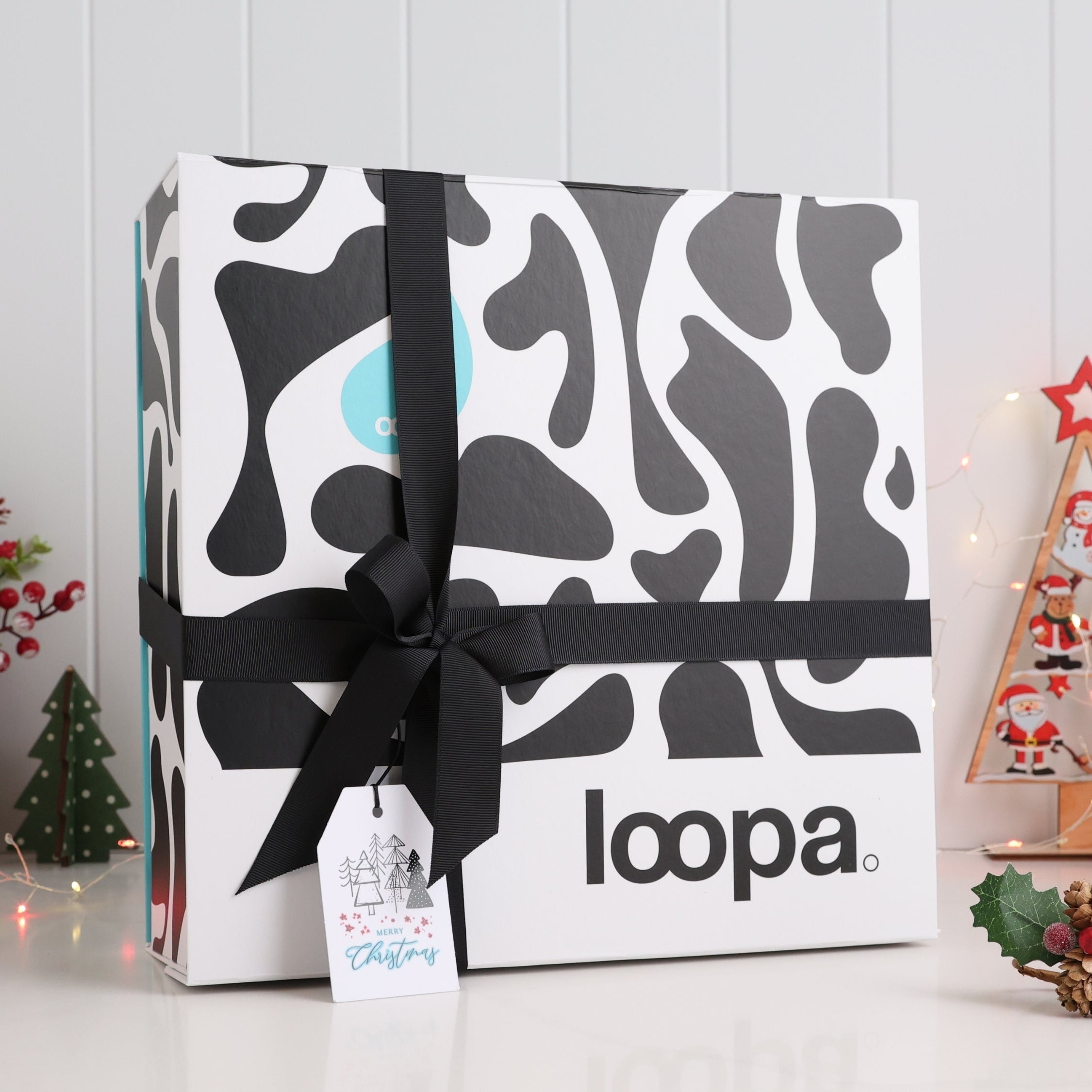 Premium Loopa Christmas gift box wrapped with black ribbon and festive tag, displayed among holiday décor. Elegant eco-friendly packaging perfect for luxury Christmas presents, seasonal home gifts and winter celebrations.
