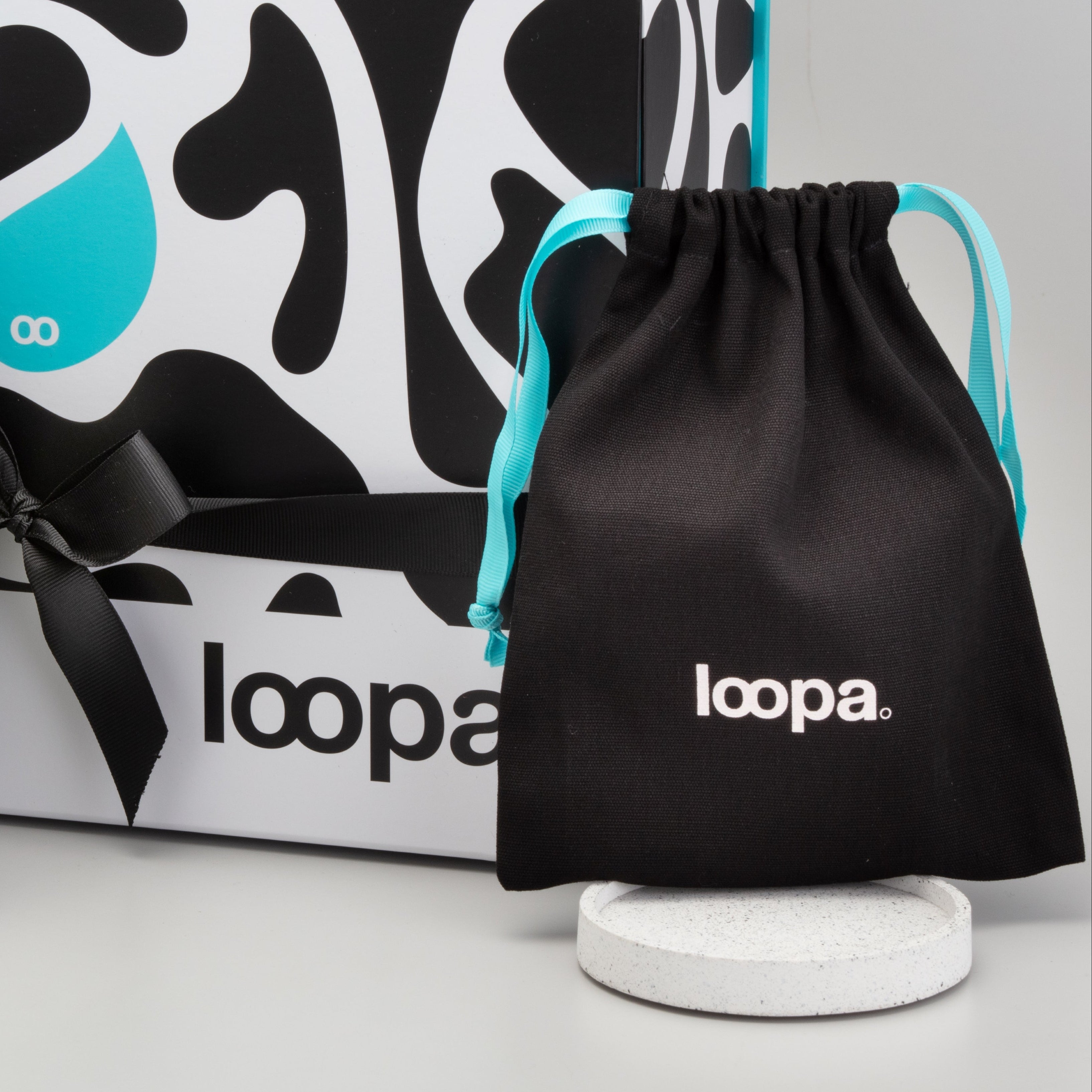 loopa skincare products including bottles and a drawstring bag with packaging in the background.