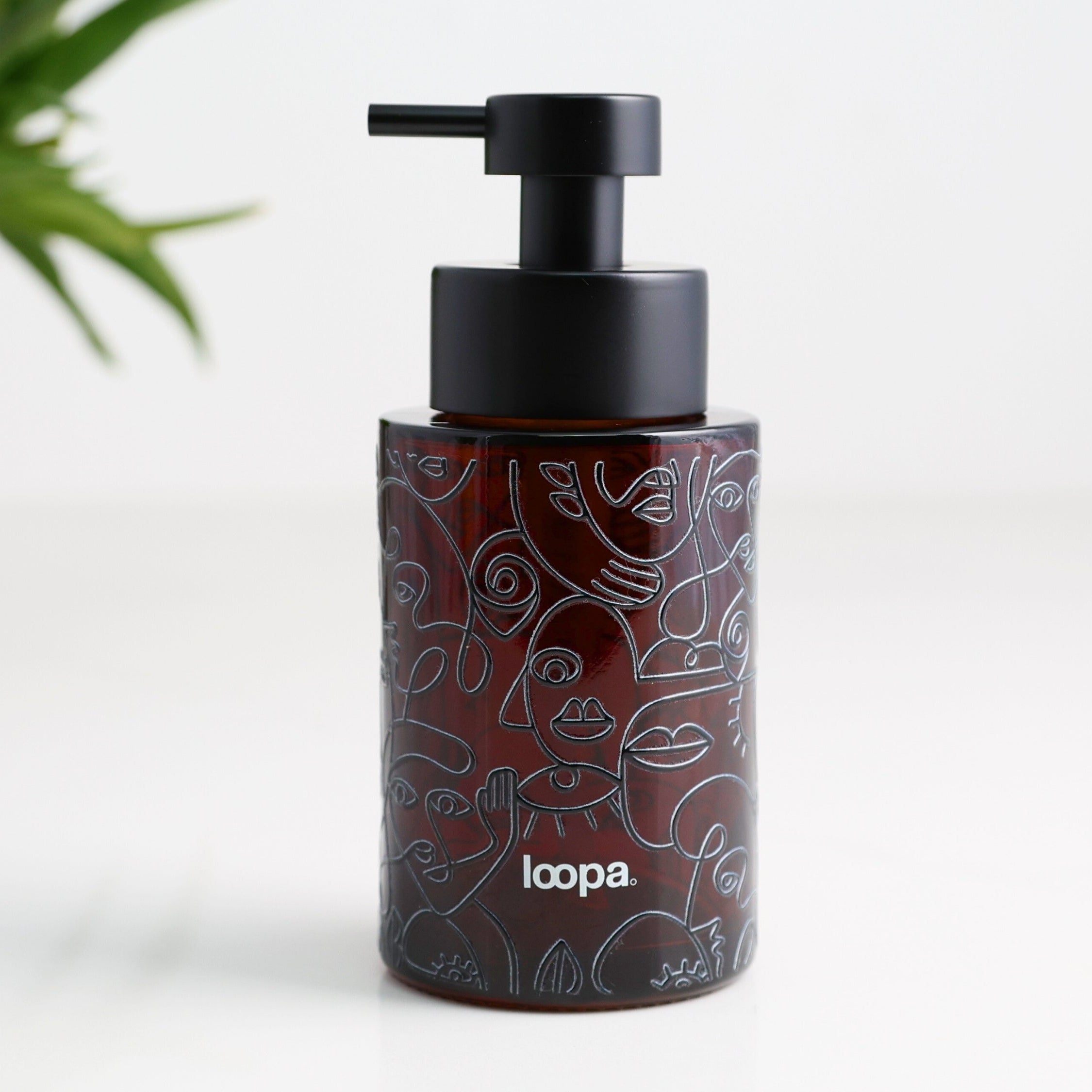 Amber glass round bottle dispenser with a black line art wrap, shown as a 250ml refillable option for soap or lotion use