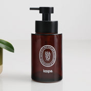 Amber glass round bottle dispenser with a white oval label, shown as a 250ml refillable bottle designed for bathrooms, cloakrooms, or WC settings