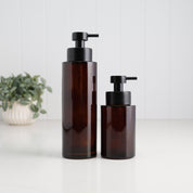 500ml and 250ml amber glass refillable soap dispensers shown together with satin black stainless steel liquid pumps, highlighting the two bottle sizes available for bathroom, kitchen or ensuite use.