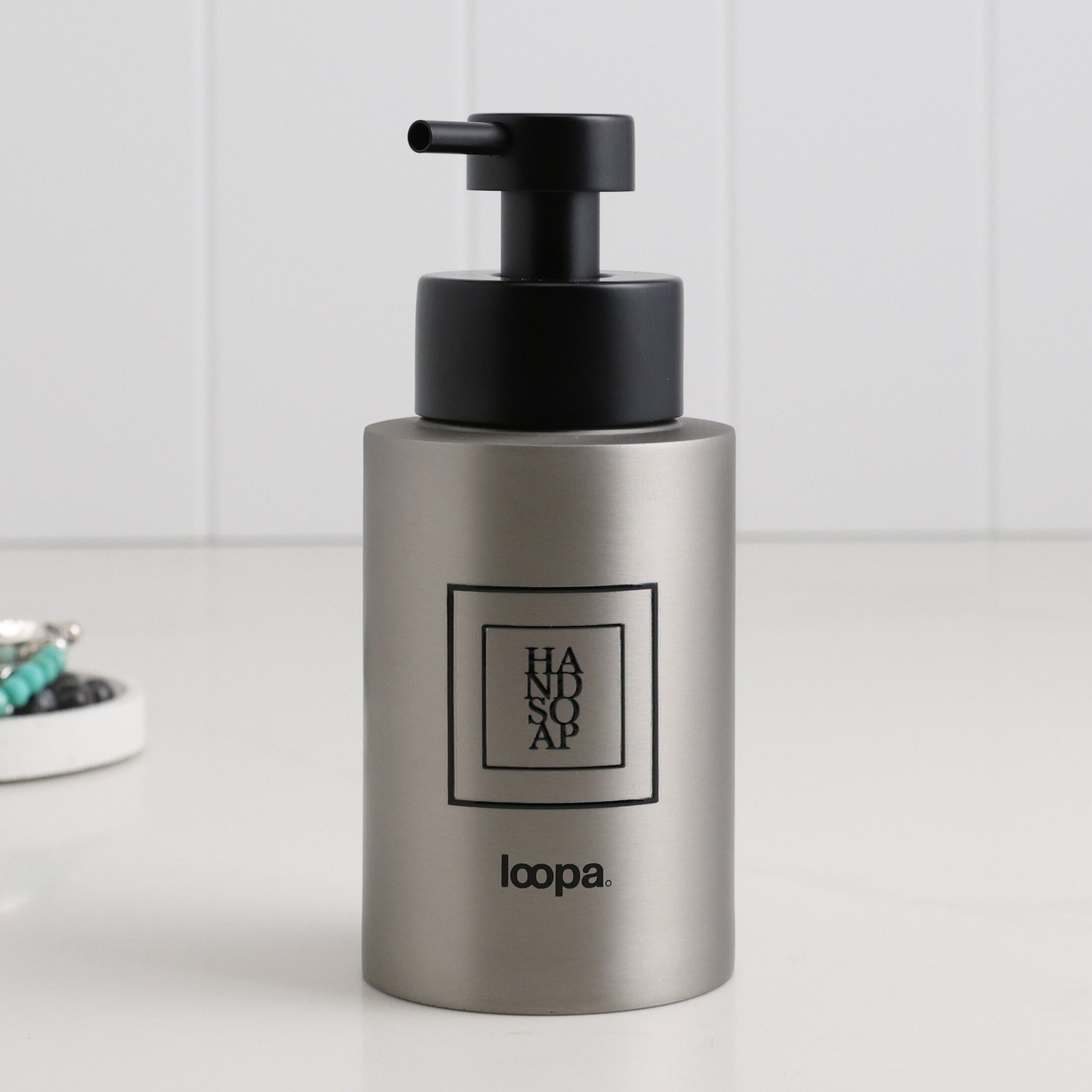 Single brushed stainless steel round bottle dispenser with a black square label, shown as a 250ml refillable bottle suited to bathrooms, cloakrooms, or WC spaces