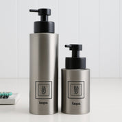 Two brushed stainless steel round bottle dispensers with black square labels, shown together in 500ml and 250ml sizes for coordinated kitchen, bathroom, or cloakroom use