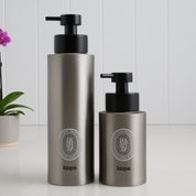 Two brushed stainless steel round bottle dispensers with white oval labels, shown together in 500ml and 250ml sizes for kitchens, bathrooms, or guest WC spaces