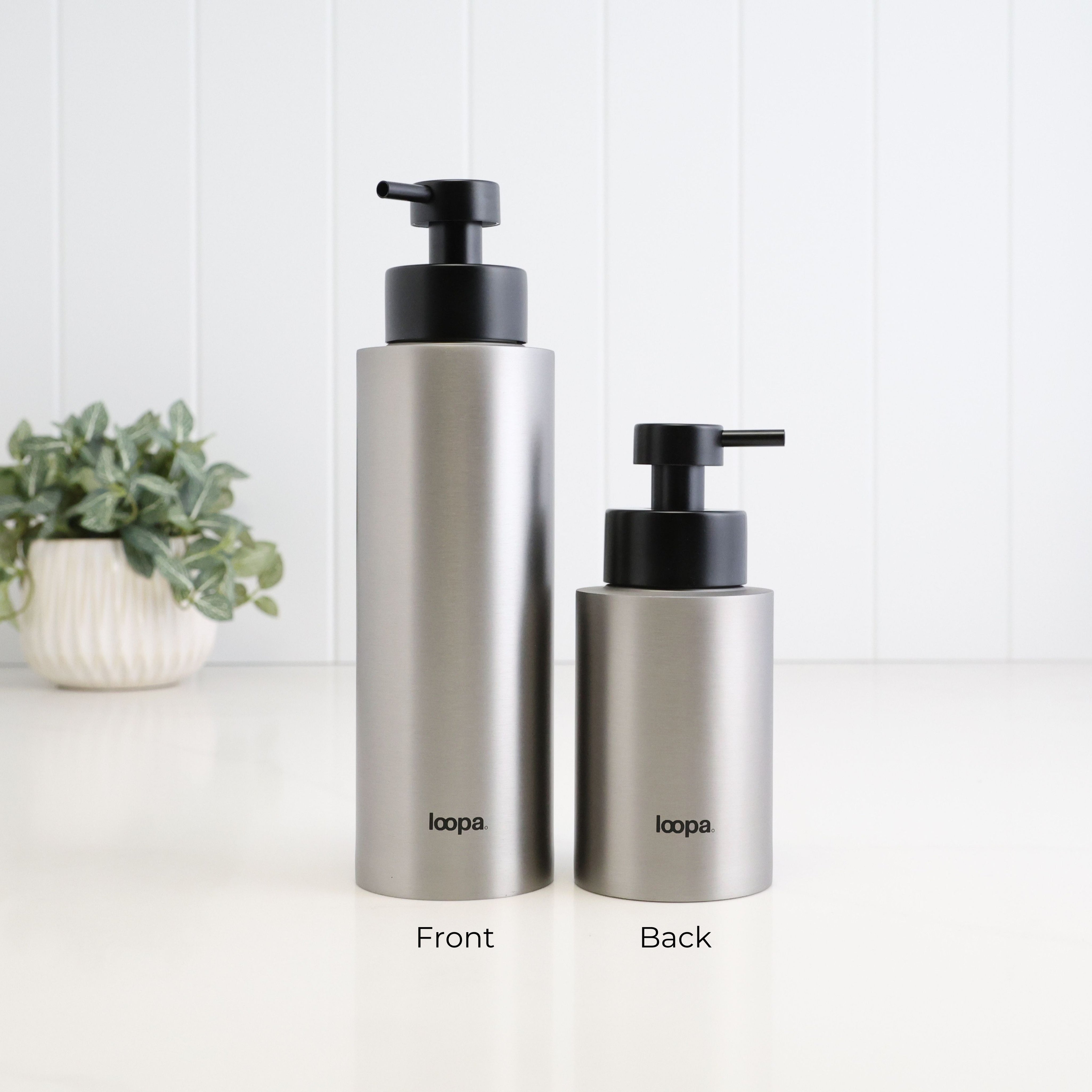 Rear view of 500ml and 250ml brushed 304 stainless steel refillable soap dispensers with black Loopa branding and satin black liquid pumps, showing the height and size difference between the two bottles.