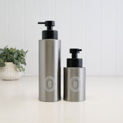 500ml and 250ml brushed 304 stainless steel soap dispensers with white round labels and satin black liquid pumps, shown together to compare the two bottle sizes.