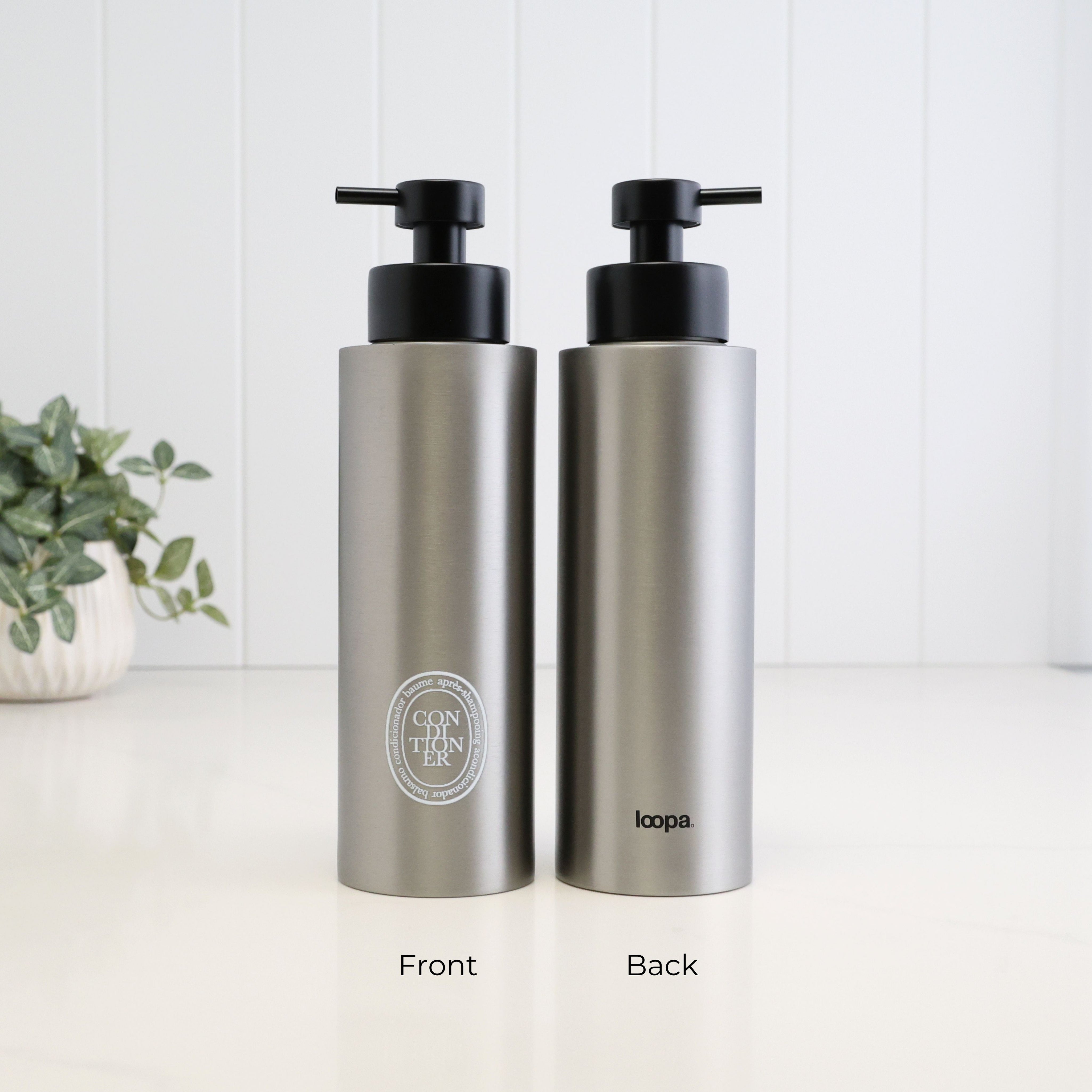Front and back view of a 500ml brushed 304 stainless steel conditioner dispenser with white oval label, Loopa branding and satin black liquid pump for a refillable shower bottle.