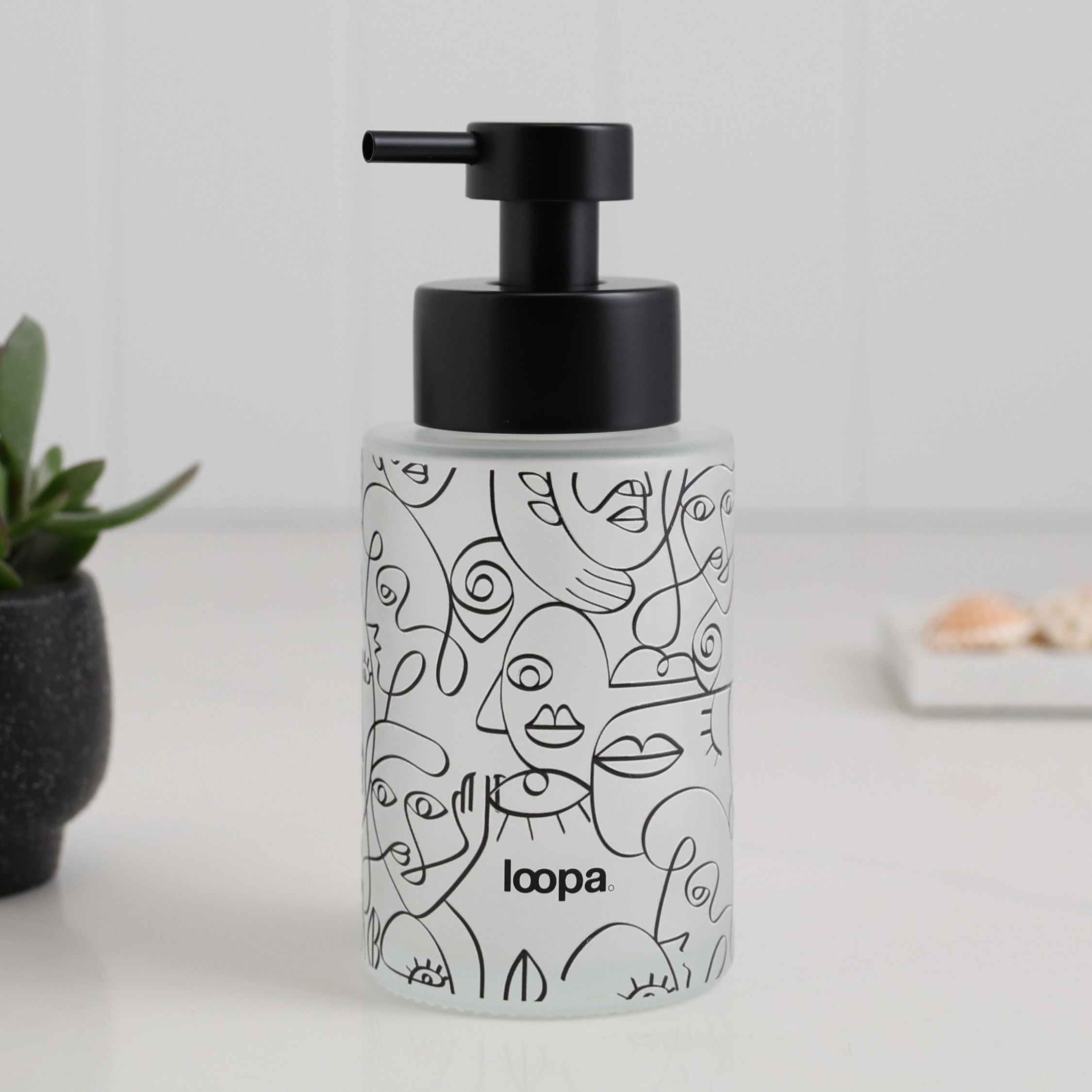 Compact frosted glass dispenser bottle with a black wrap finish, created for refillable hand soap or lotion in everyday spaces