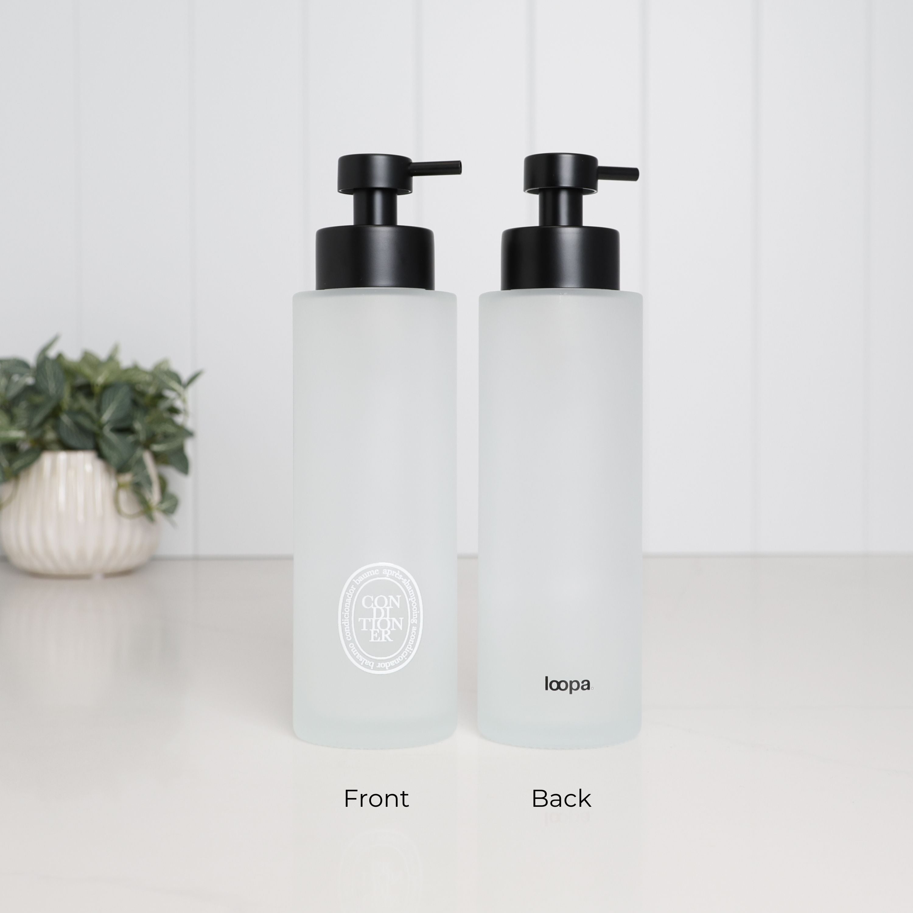 Front and back view of a 500ml frosted glass conditioner dispenser with white oval label, Loopa branding and satin black stainless steel pump.