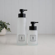 Matching frosted glass dispenser set with tall 500ml dish soap bottle and 250ml hand soap bottle, finished with black square labels and satin black stainless steel pumps for a coordinated kitchen sink setup.