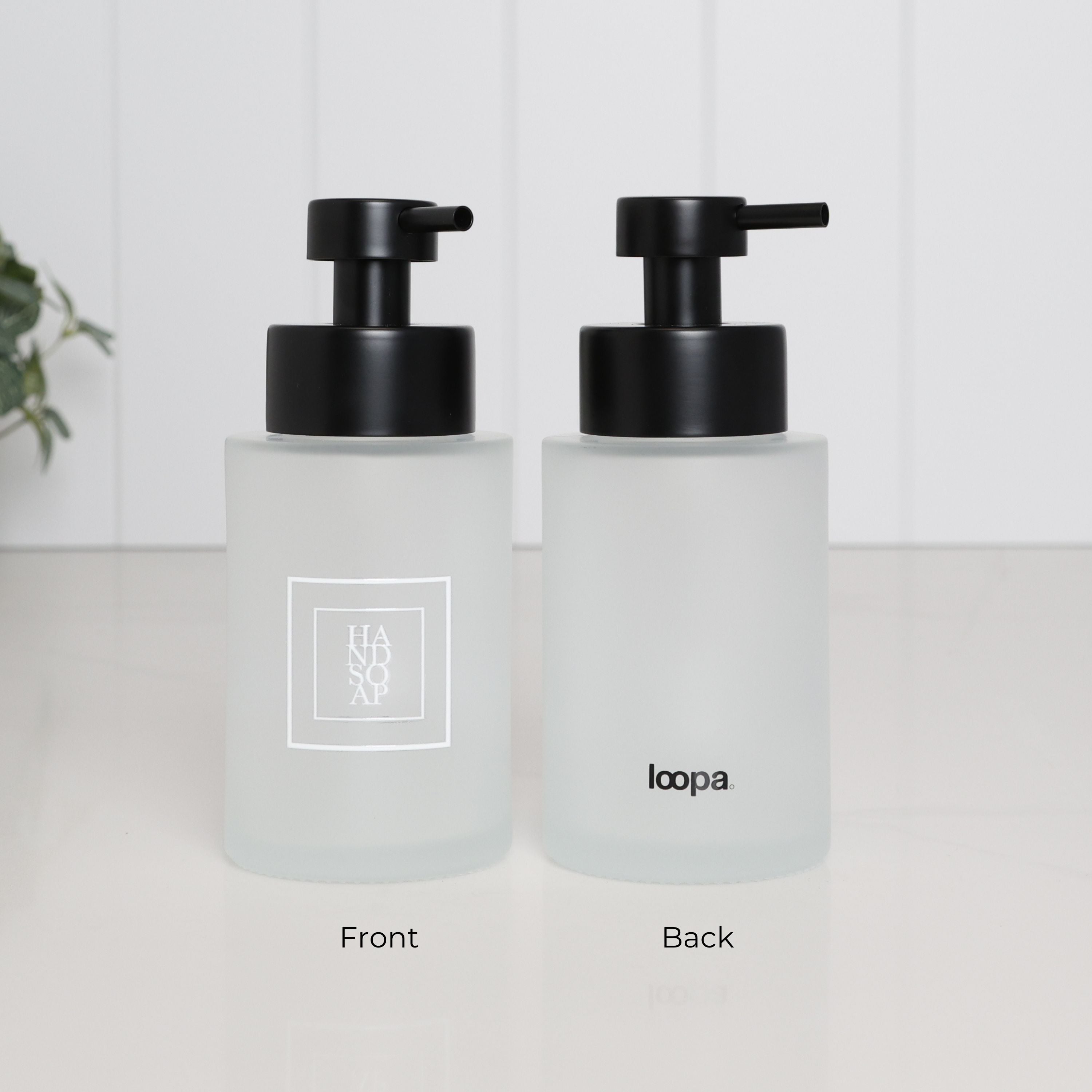 250ml frosted glass hand soap dispenser with white square Hand Soap label and satin black stainless steel pump, shown held in hand to demonstrate the compact size of the refillable bathroom sink bottle.