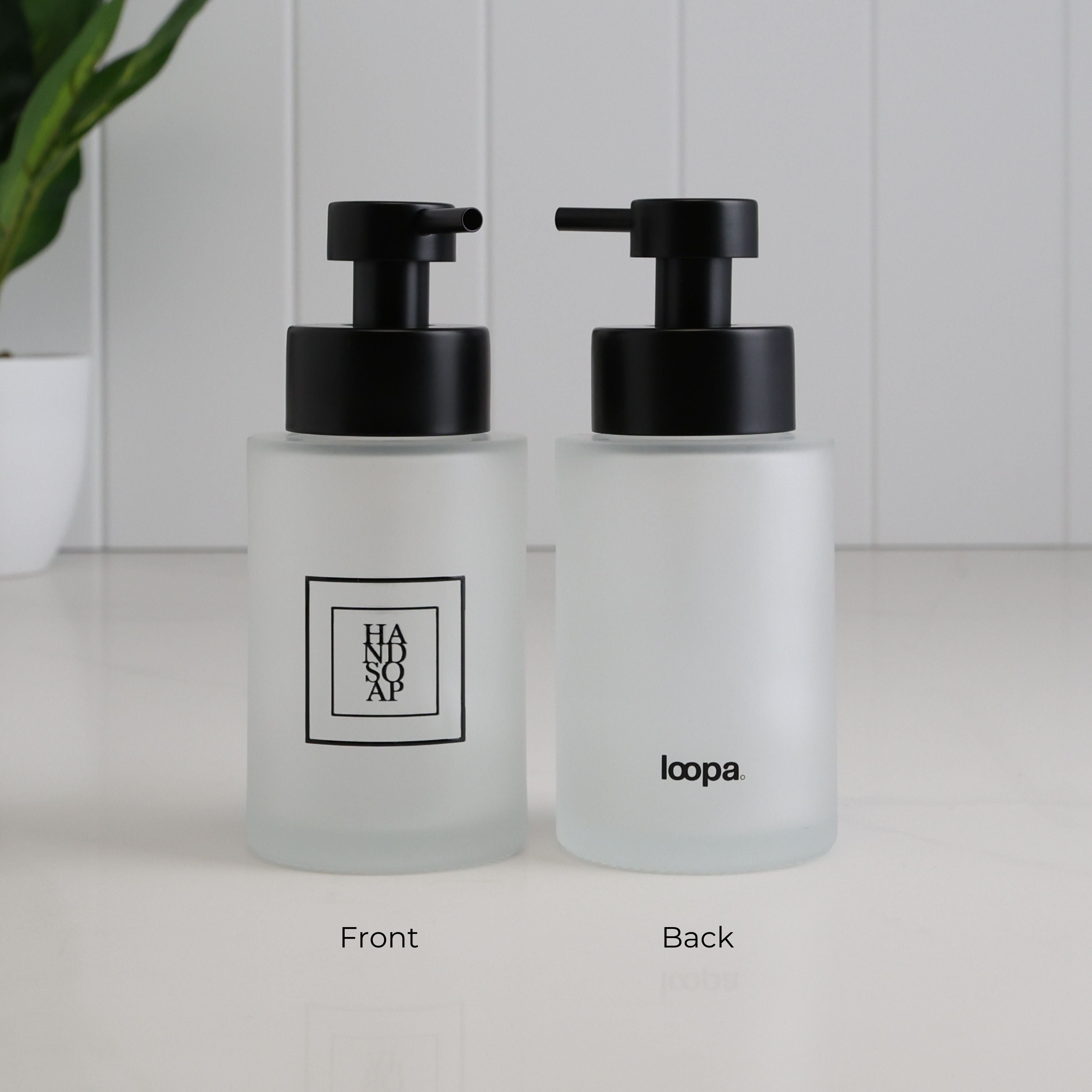 Front and back view of a 250ml frosted glass hand soap dispenser with black square label, Loopa branding and satin black stainless steel liquid pump.