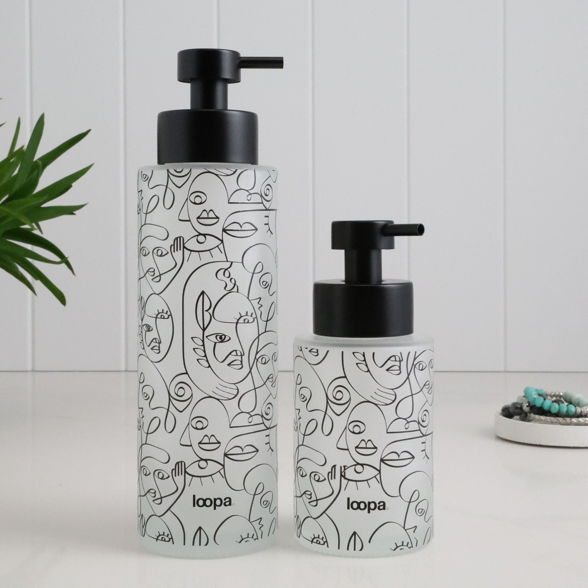Frosted glass dispenser bottle with a black wrap label, designed for refillable soap or lotion in modern home spaces