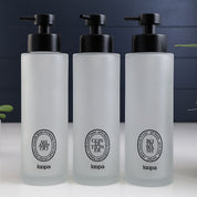 Tall frosted glass round bottle dispenser featuring a black oval label, shown as a 500ml refillable option for soap or lotion use
