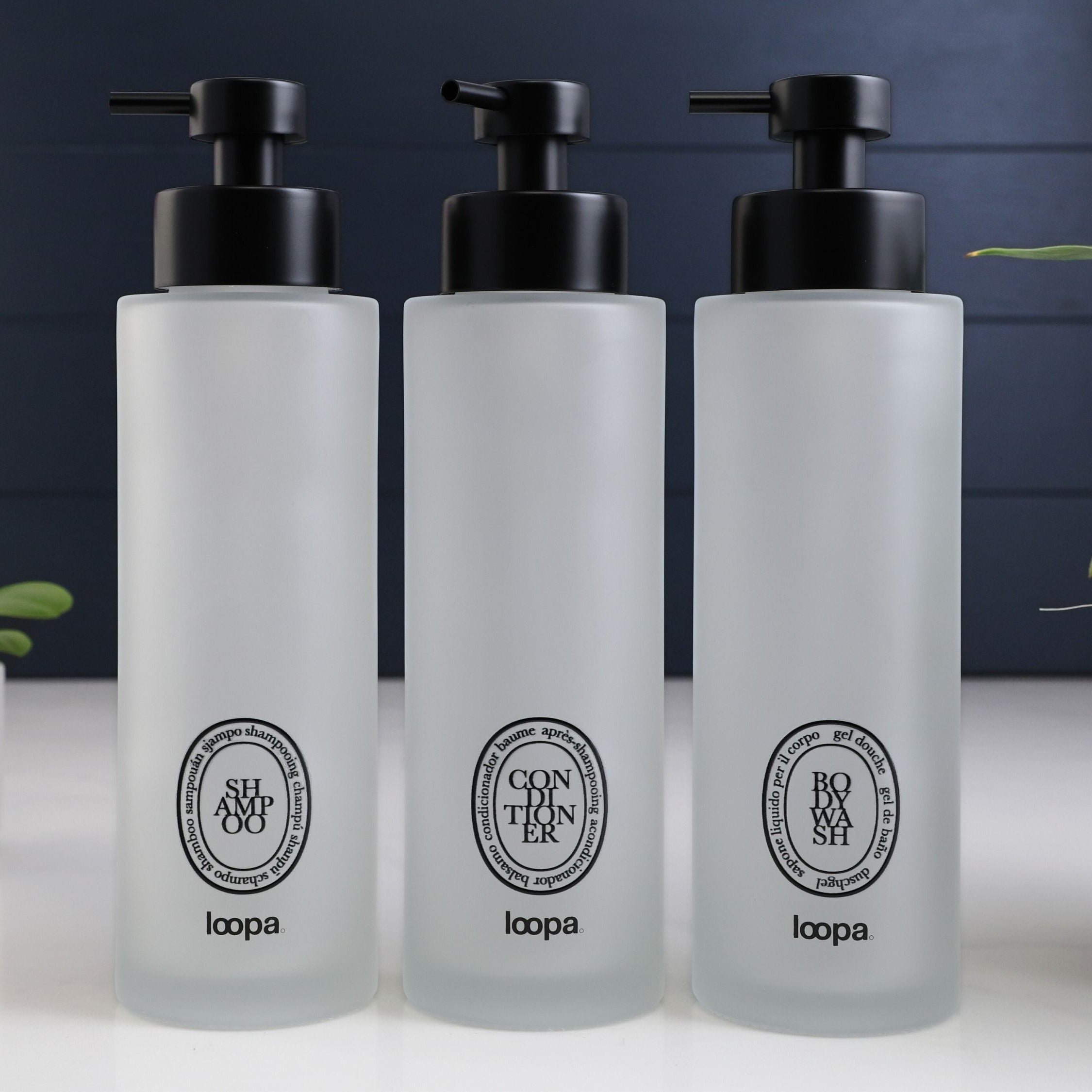 Tall frosted glass round bottle dispenser featuring a black oval label, shown as a 500ml refillable option for soap or lotion use