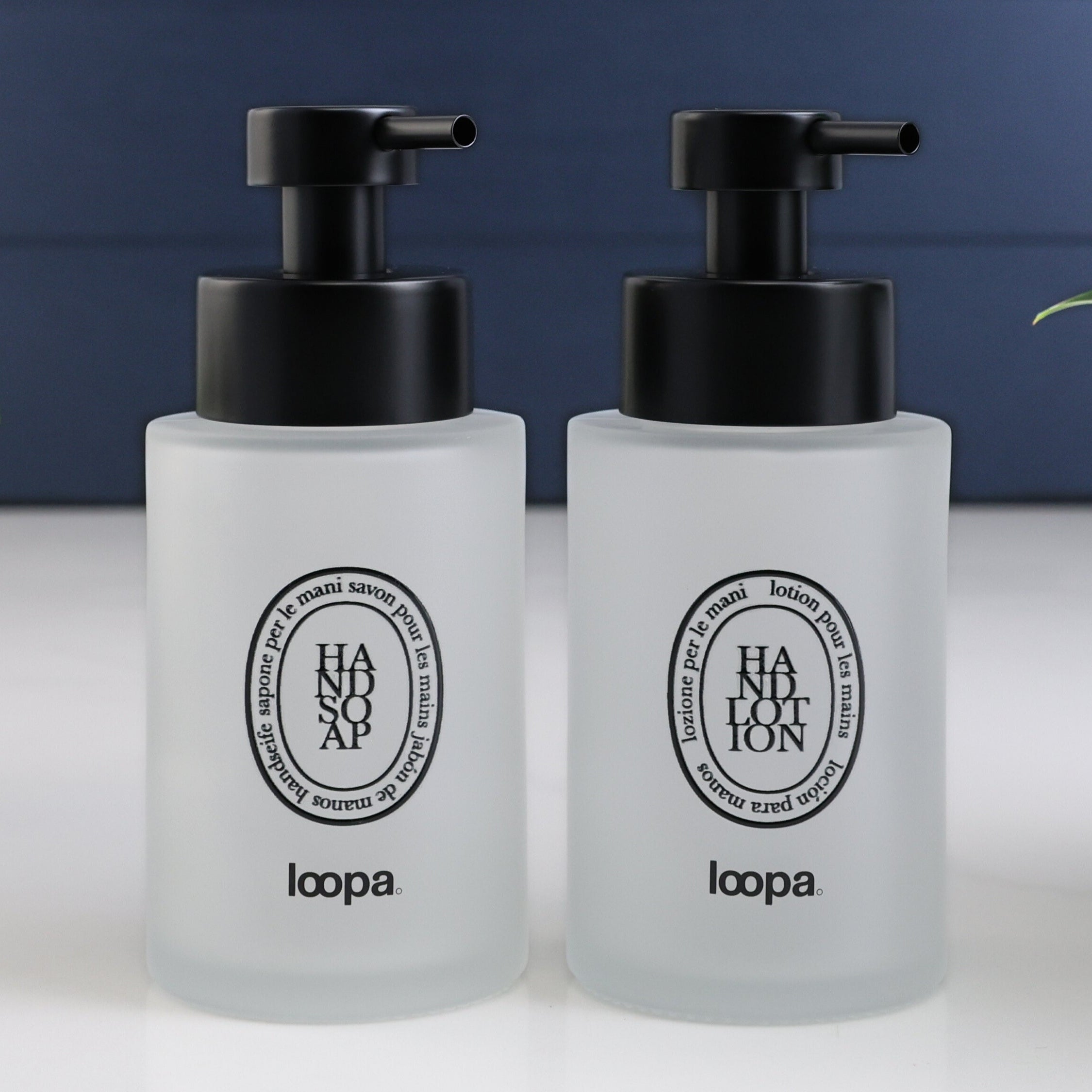 Two frosted glass round bottle dispensers with black oval labels, shown as matching 250ml refillable options for soap or lotion