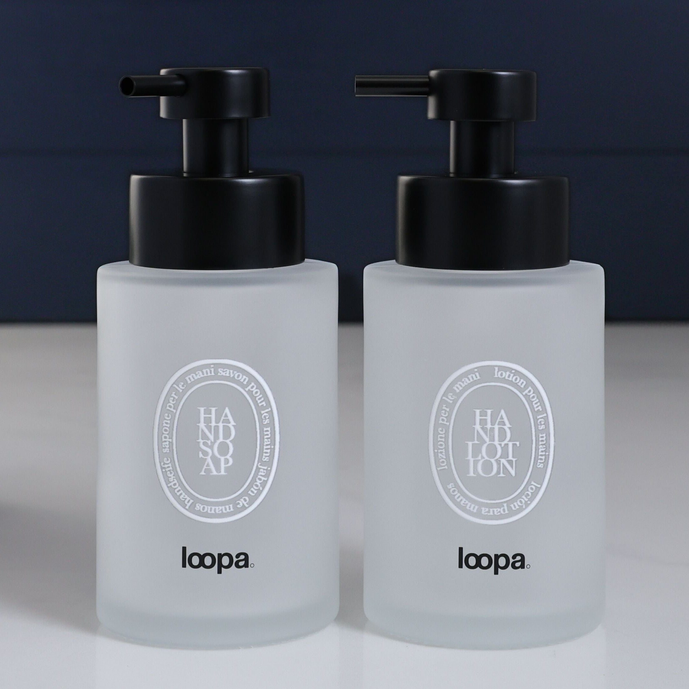 Compact frosted glass round bottle dispenser with a white oval label, designed for refillable soap or lotion in modern home settings