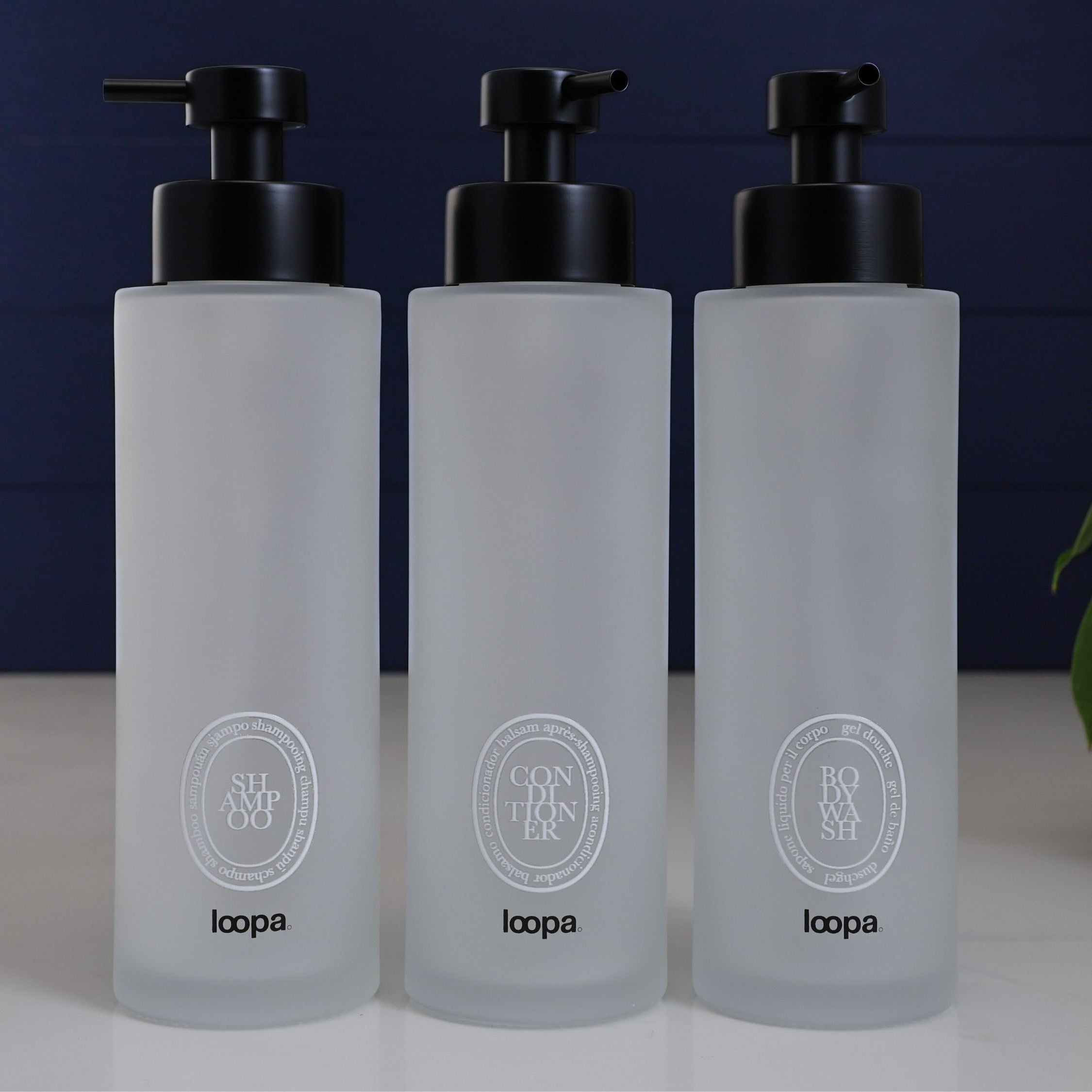 Tall frosted glass round bottle dispenser with a white oval label, created for refillable soap or lotion in contemporary home spaces