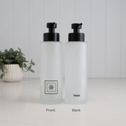 Front and back view of a 500ml frosted glass shampoo dispenser with black square label, Loopa branding and satin black stainless steel liquid pump.