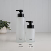 Back view of 500ml and 250ml frosted glass soap dispensers shown side by side for size comparison, with Loopa branding and satin black stainless steel pumps.
