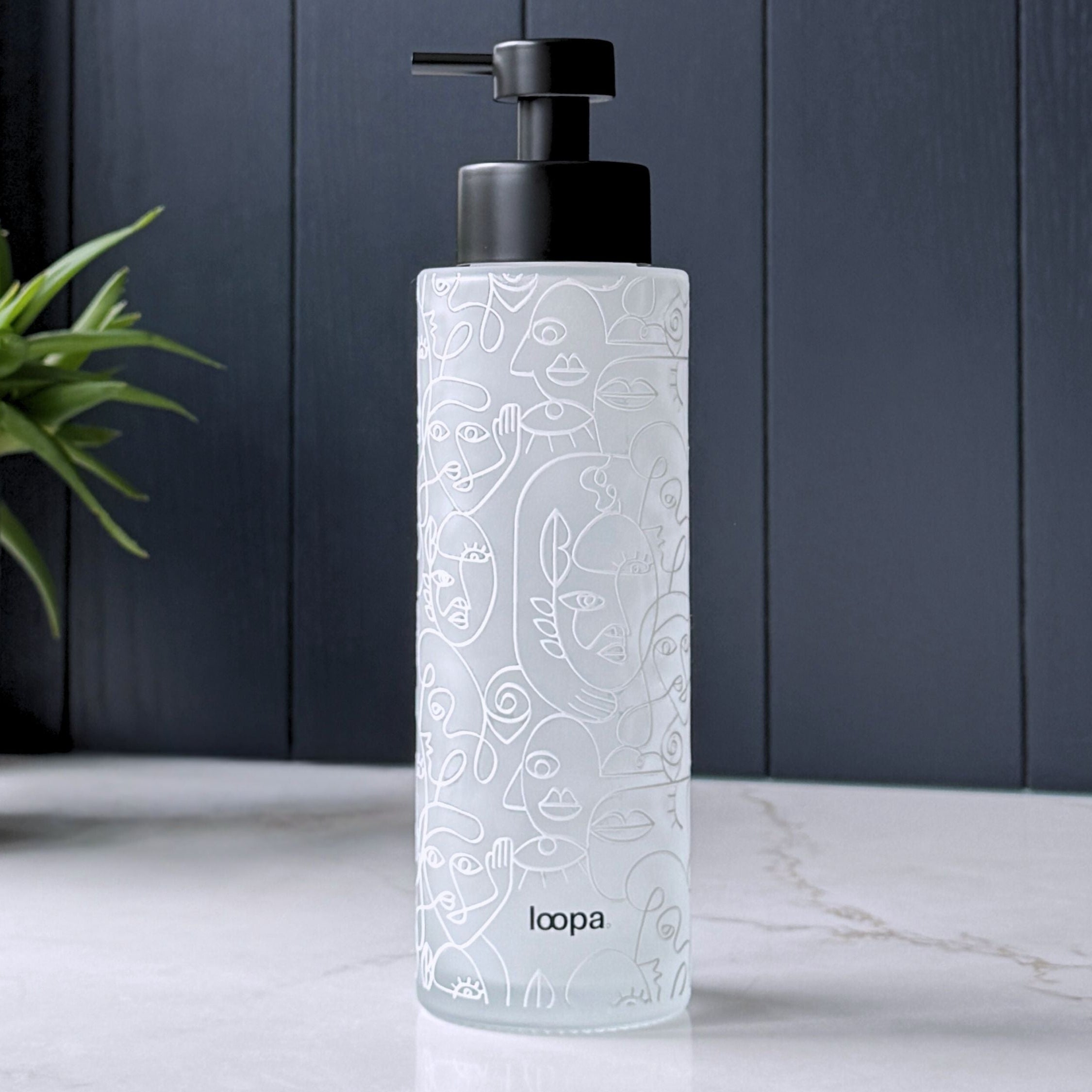 Frosted glass soap dispenser bottle with a white wrap label, designed as a refillable piece for modern kitchen or bathroom spaces