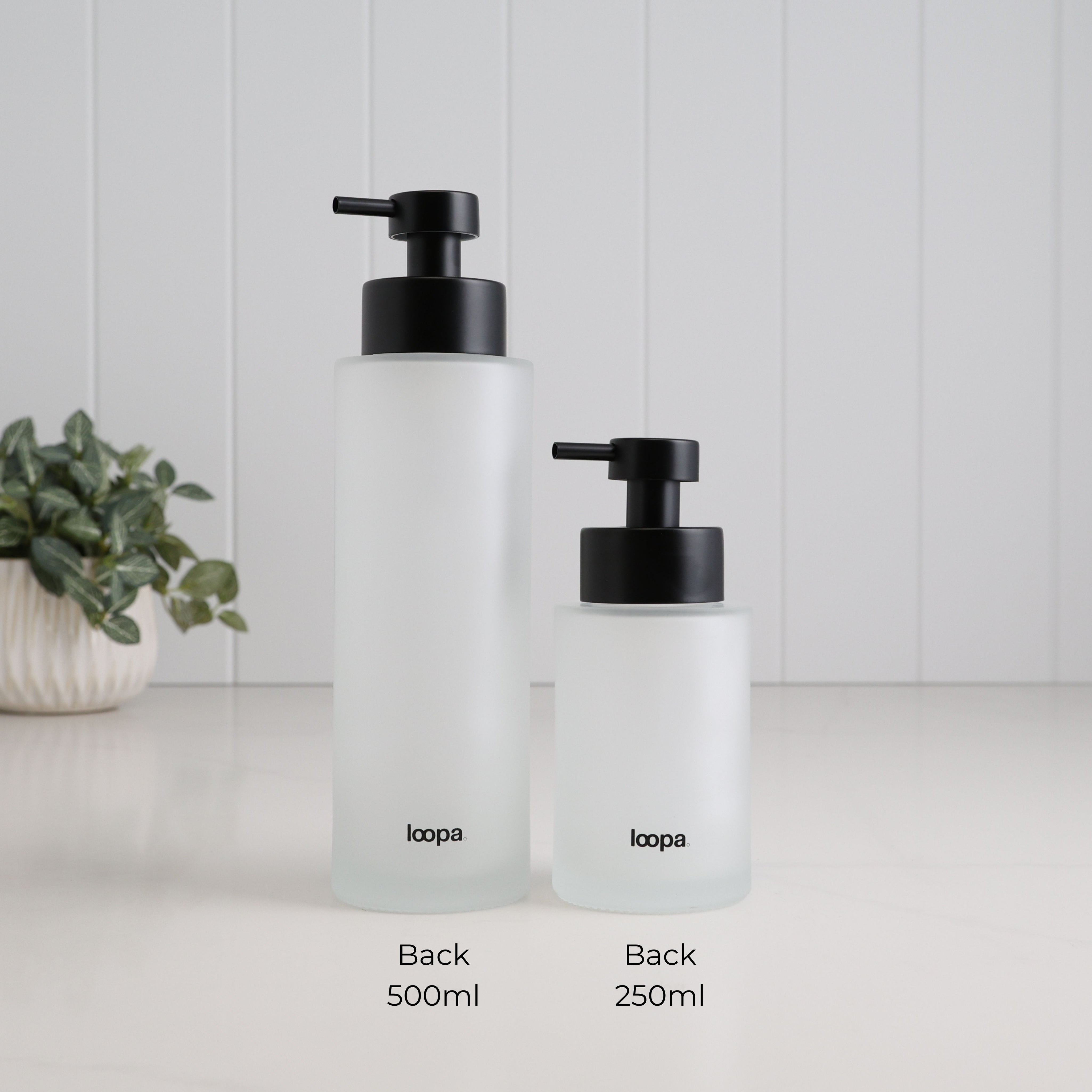 Back view of 500ml and 250ml frosted glass refillable soap dispensers with Loopa branding and matching satin black liquid pumps, clearly showing both bottle sizes side by side.