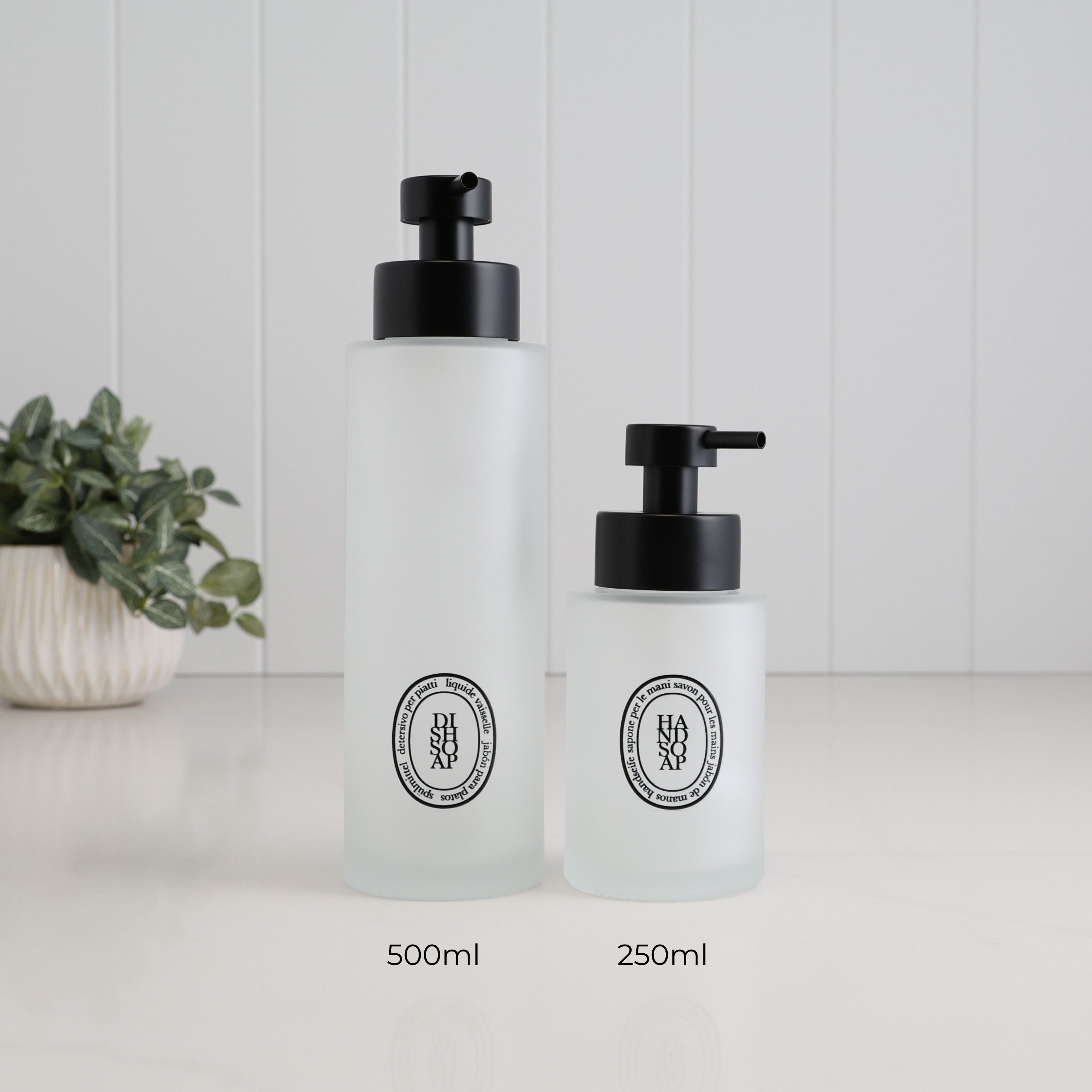 500ml and 250ml frosted glass soap dispensers with black oval dish soap and hand soap labels and satin black pumps, showing the two refillable bottle size options.