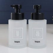 Compact square frosted glass bottle dispenser with a white label, created for refillable soap or lotion in everyday home use
