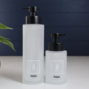 Square frosted glass dispenser bottle with a clean white label, presented as a refillable option for contemporary kitchen or bathroom use