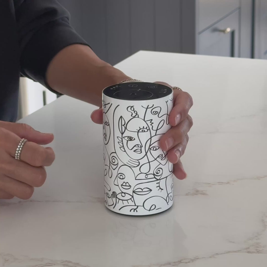 Video demonstrating the Loopa white waterless essential oil diffuser with black abstract face line art. A person holds and rotates the cylindrical metal diffuser to show its decorative design, compact size and top control panel. This portable rechargeable aromatherapy diffuser uses essential oils directly without water or heat, making it suitable for home fragrance in bedrooms, living rooms and offices.