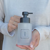 Video showing a 250ml frosted glass hand soap dispenser with black square label and satin black stainless steel liquid pump, held to show the bottle size and finish.