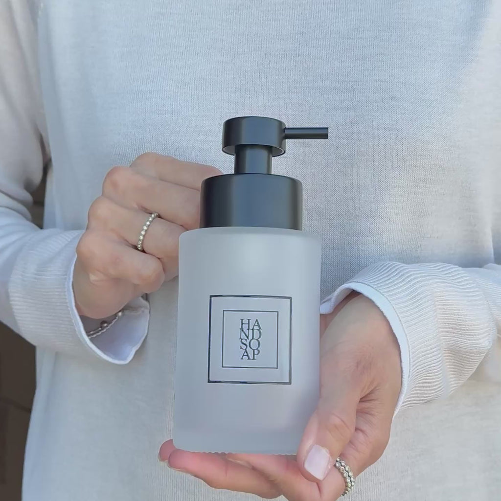 Video showing a 250ml frosted glass hand soap dispenser with black square label and satin black stainless steel liquid pump, held to show the bottle size and finish.