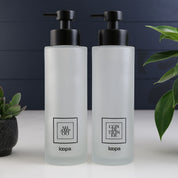 Square frosted glass bottle dispenser with a black label, created for refillable hand soap or lotion in modern interiors