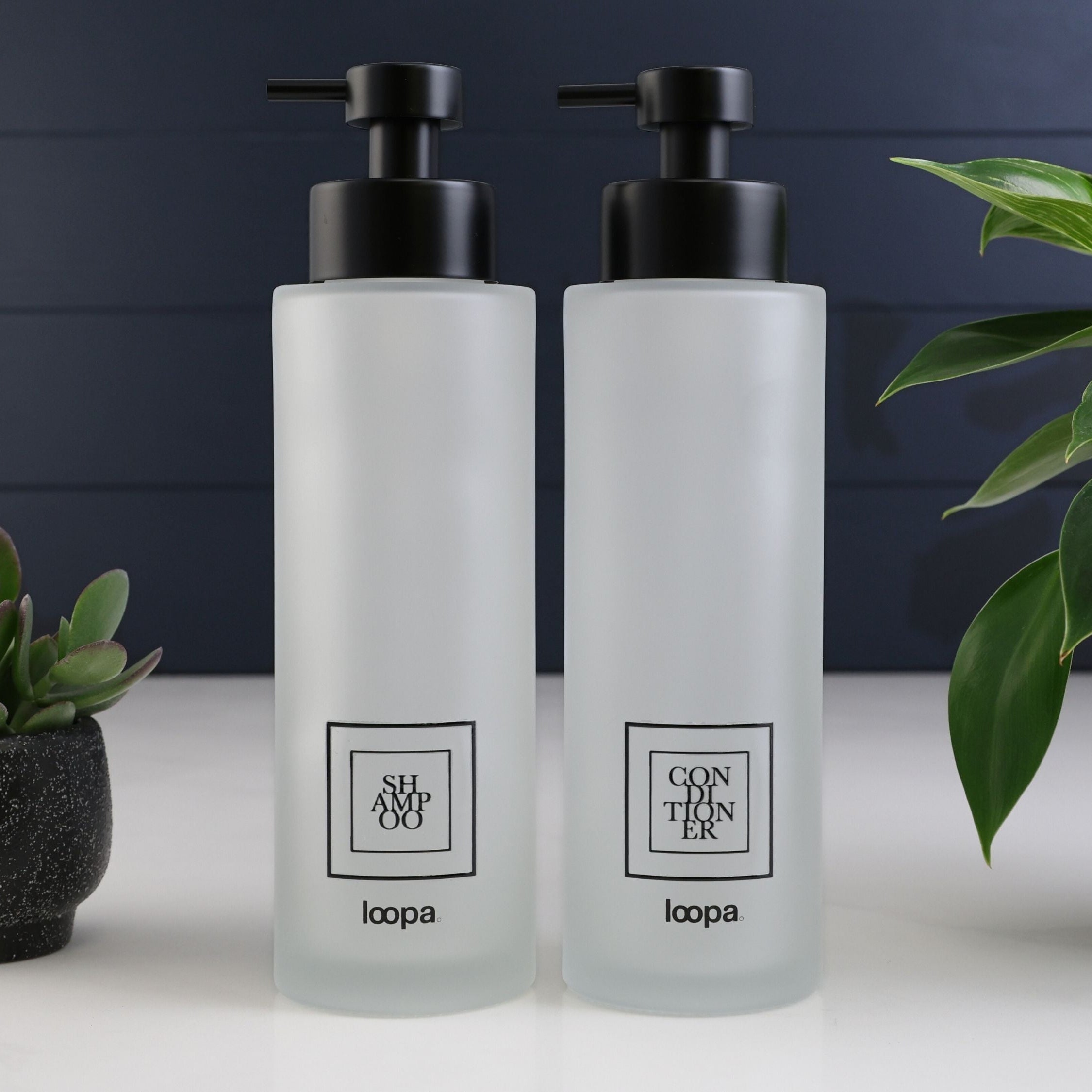 Square frosted glass bottle dispenser with a black label, created for refillable hand soap or lotion in modern interiors